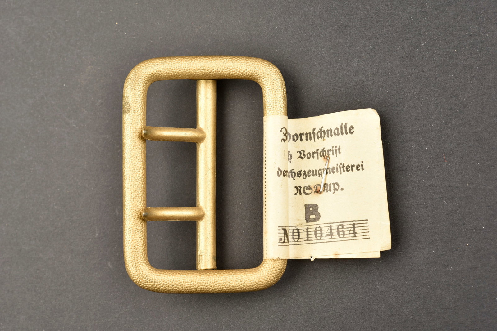 Boucle de ceinturon RZM. RZM belt buckle.: Boucle de ceinturon RZM. En metal grenele or, boucle a deux ardillons complete. Etiquette RZM numero 010464. Boucle marquee RZM M5/71, correspondant au fabricant Overhoff & Cie., Ludenscheid. A noter 