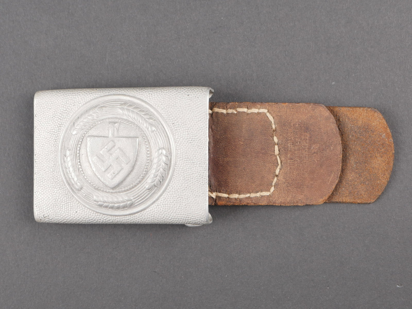 Boucle de ceinturon RAD. RAD belt buckle.: Boucle de ceinturon RAD. En aluminium. Bel insigne en relief. Boucle a deux ardillons complete. Fabrication BH 38. Patte en cuir presente mais fortement usee. Marquages illisibles. A noter une certain