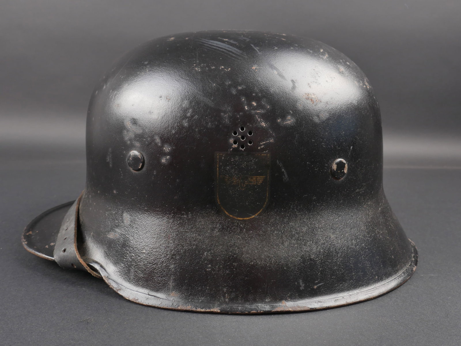 Casque de la Reichsbahn. Reichsbahn helmet.: Casque de la Reichsbahn. Coque en metal. Peinture noire a 80%. Couleur nationale a 80%. Insigne de la Reichsbahn a 50%, partiellement recouvert d un voile de peinture noire. Coiffe en cuir complete. T