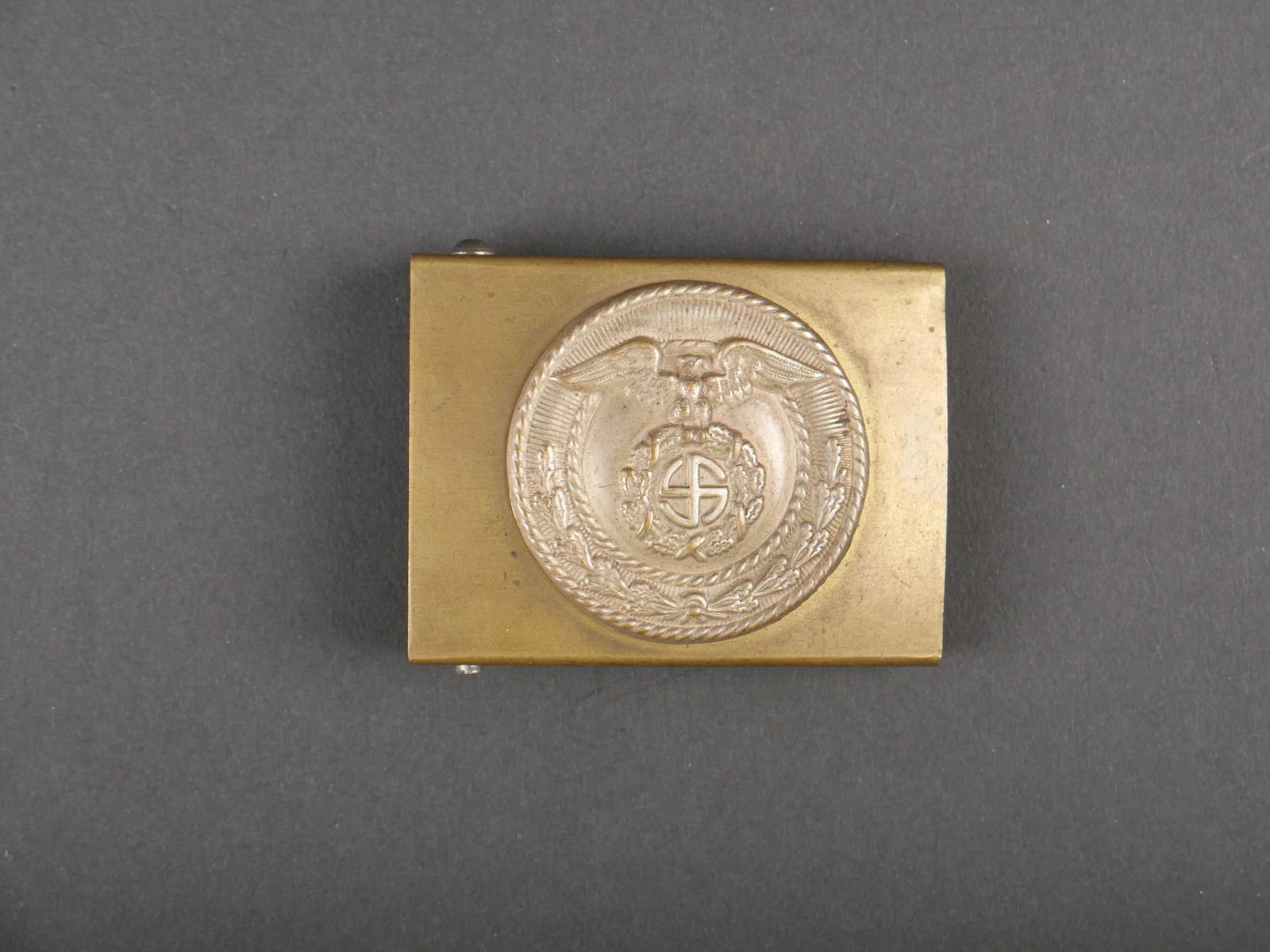 Boucle de ceinturon SA. German SA belt buckle.: Boucle de ceinturon de la SA. En laiton, fabrication en deux parties. Soudure arriere posterieure. Boucle a deux ardillons presente. Sans marquages visibles. A noter une certaine usure et patine de la