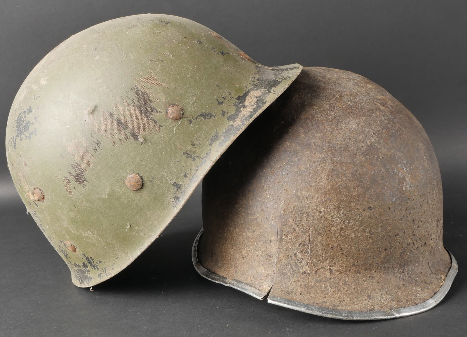 Casque USM1. US M1 Helmet.: Casque USM1 compose d’une coque dont le jonc est ferme a l’avant. On observe plusieurs fissures sur les cotes de la coque. Les pontets sont fixes et les jugulaires absentes. L’exterieur presente