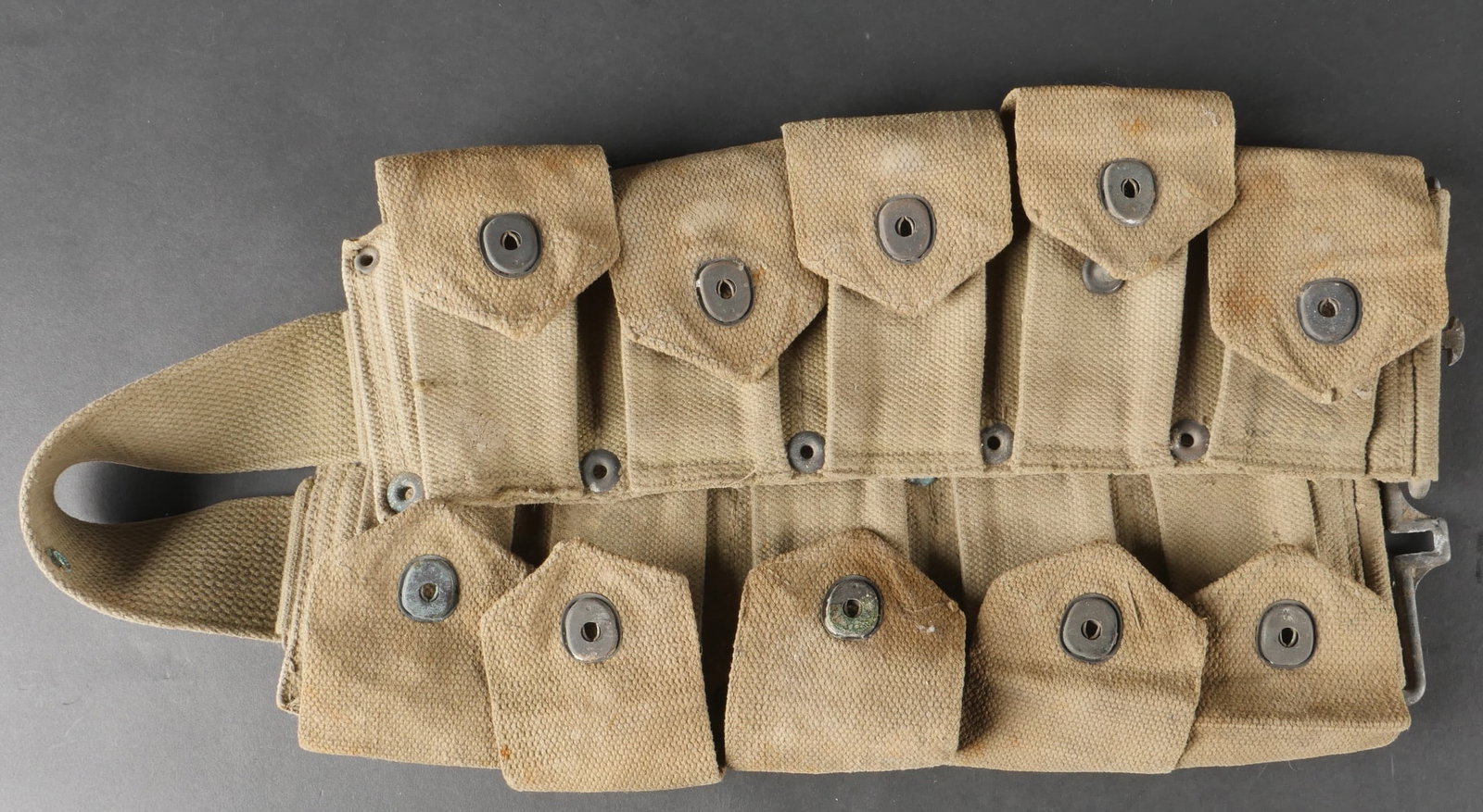 Ceinturon Garand. US Garand ammunition belt.: Ceinturon destine au fusil Garand, realise en toile robuste de teinte OD3. L’ensemble des rabats est present. Un marquage US bien visible orne la face avant du ceinturon. Les boutonpression sont par