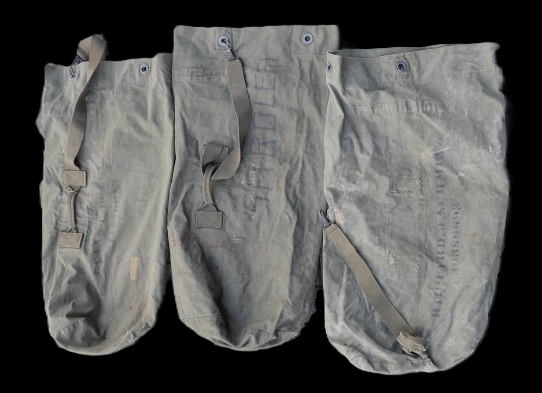 Sacs a paquetage nominatif US. Set of named US pack bags: Ensemble de sacs a paquetage nominatif americains comprenant un premier sac en toile epaisse OD7, avec une attache presente mais decousue. Il porte l’indication nominative Richard J Schmitz 39389693