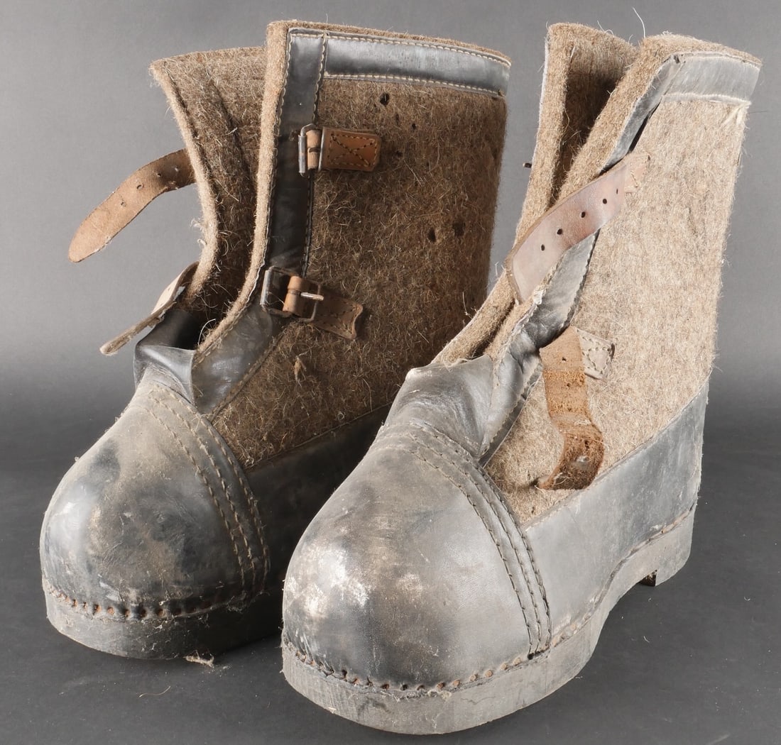 Bottes de garde allemande. German sentry boots: Paire de bottes de garde allemandes homogene, confectionnee en cuir noir associe a du feutre de couleur marron. Les semelles sont realisees en bois. Les sangles de fermeture sont presentes, bien qu’