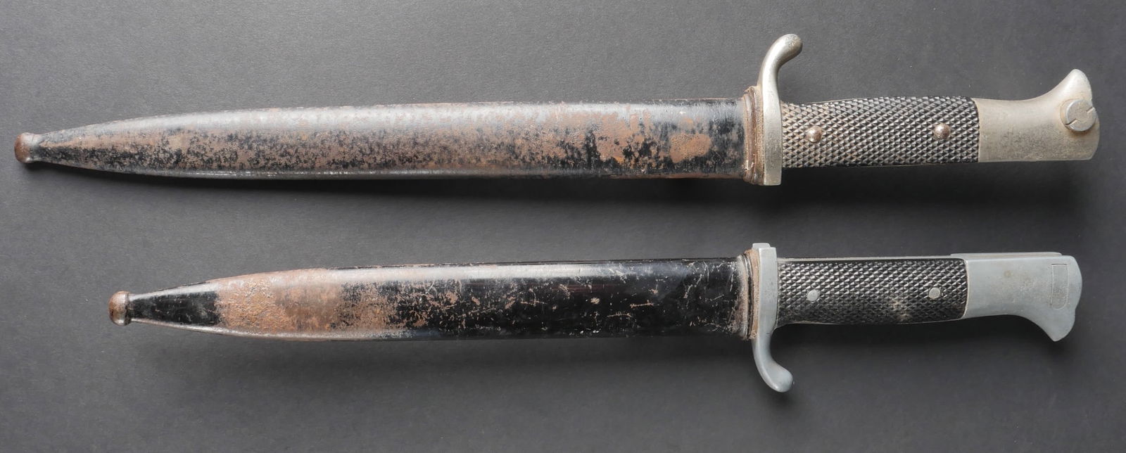 Baionnettes allemande. German Bayonets.: Deux baionnettes allemandes. L’ensemble comprend une premiere baionnette dont les garnitures metalliques presentent une oxydation, avec des plaquettes en bakelite et un fourreau egalement oxyde, con