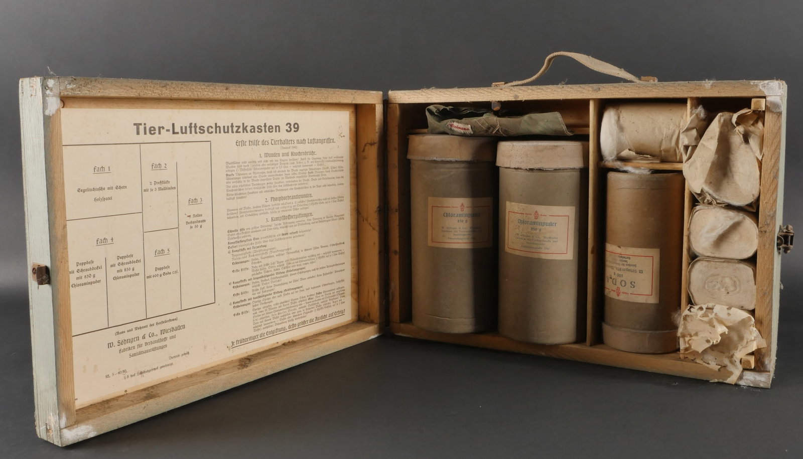Tierluftschutzkasten. Animal air raid protection box: Tierluftschutzkasten, caisse en bois recouverte a environ 80?% de sa peinture d’origine de teinte grise. Poignee de transport en toile presente. Les crochets de fermeture en metal sont fonctionnels 