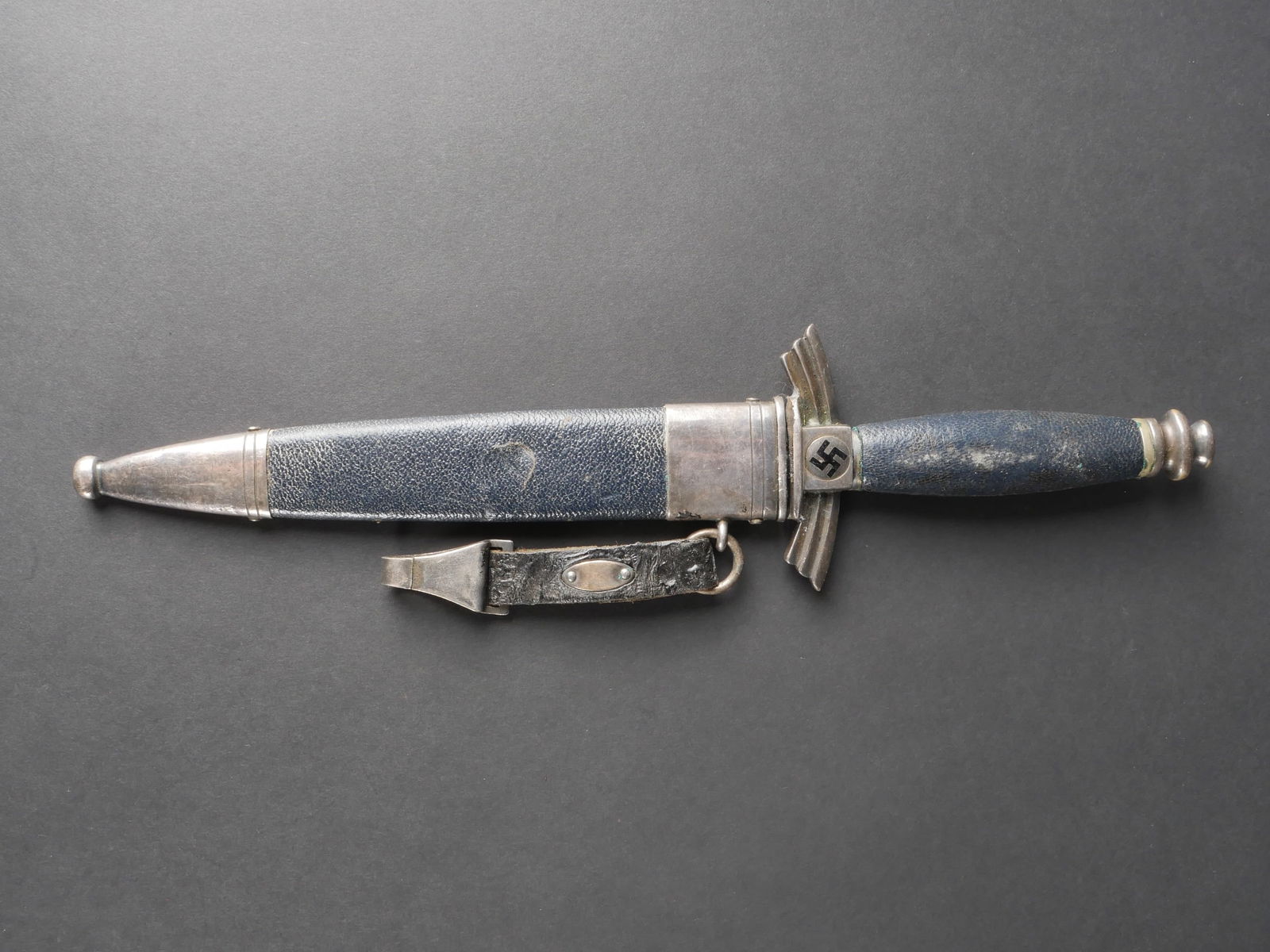 Dague DLV. German DLV Dagger.: Dague du DLV. Garnitures en metal a finition argentee. La poignee est gainee de cuir noir, presentant quelques rayures. La teinte noire des emblemes nationaux est encore visible. Fourreau en metal de