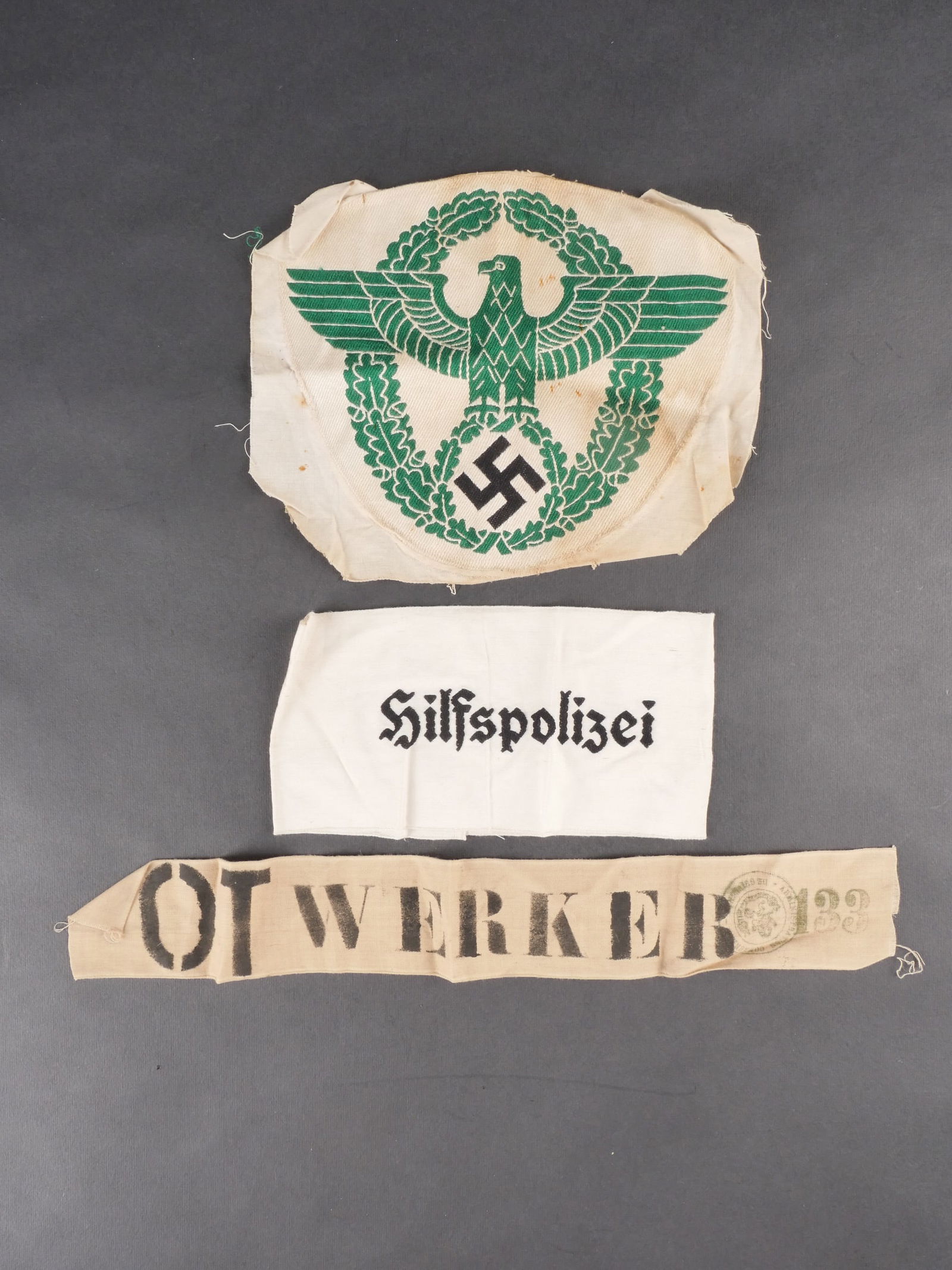 Brassards Polizei. Polizei armbands.: Ensemble de brassards de la Polizei comprenant un brassard en tissu coton avec marquages imprimes OT Werker 133 et tampon illisible, ainsi qu’un brassard en tissu blanc portant les marquages tisses