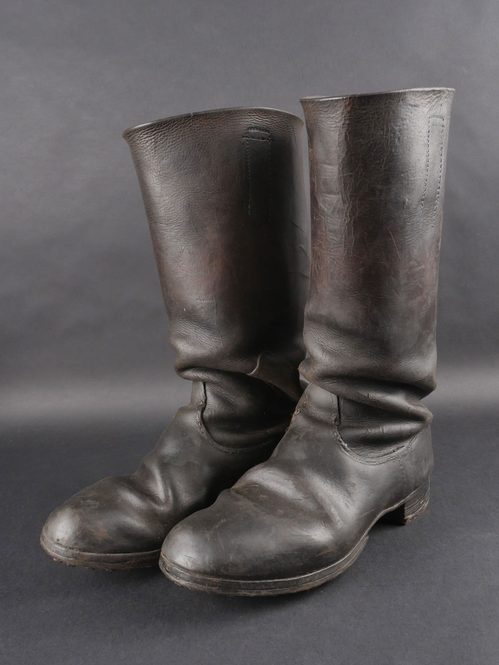 Bottes allemande. German Boots: Bottes allemandes. Paire homogene en cuir noir. Sans marquage visible. Talons ferres et semelles cloutees. Pointure approximative 42/43 francaise. Dechirures visibles. Cuir fortement graisse. Presente