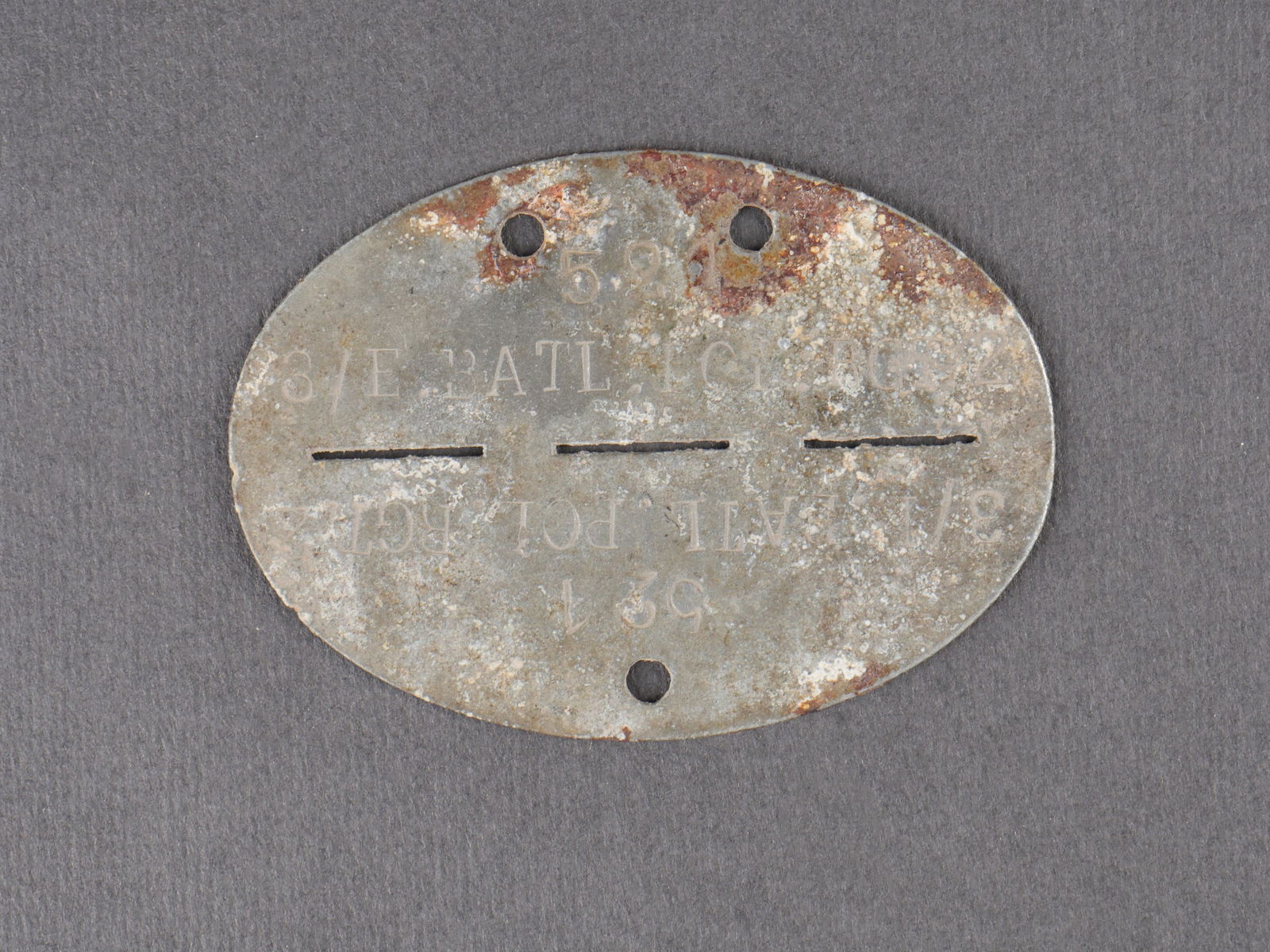 Plaque d identite Polizei. Polizei dog tag.: Plaque d identite de la Polizei en metal fortement oxydee, marquages 3/E.BATL.POL.RGT, numero 521. Usure marquee et forte oxydation visibles. etat II+. Heavily oxidized metal Polizei identification ta