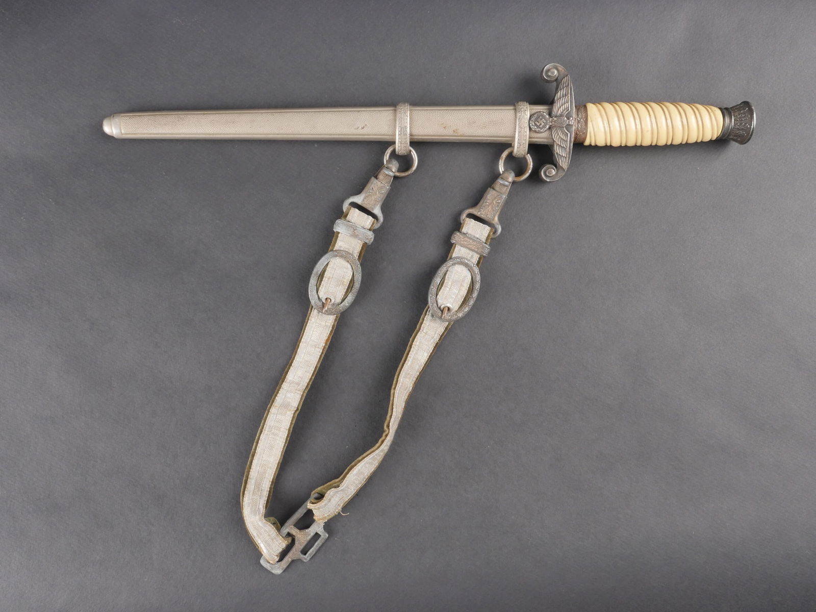 Dague de la Heer. German Heer dagger.: Dague de la Heer dont les garnitures en metal presentent des traces d’oxydation. La poignee, en bakelite blanche, est en bon etat. La lame, bien conservee, presente une oxydation partielle. Il s’a