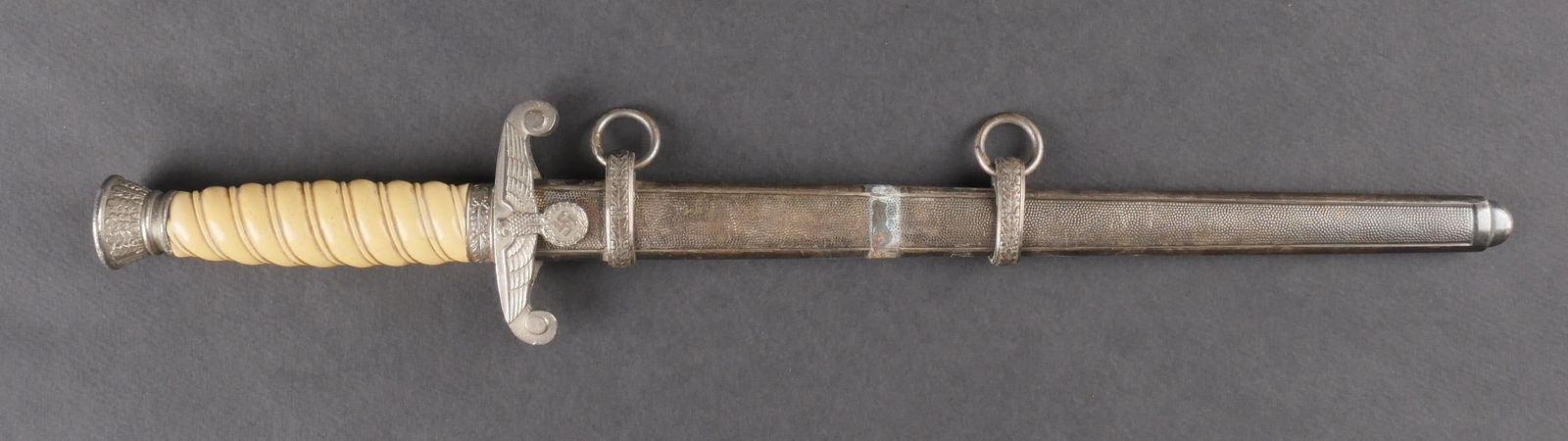 Dague de la Heer. German Heer dagger.: Dague de la Heer dont les garnitures en metal presentent des traces d’oxydation. La poignee en bakelite blanche est en bon etat. La lame, bien conservee, presente une oxydation partielle. Il s’agi