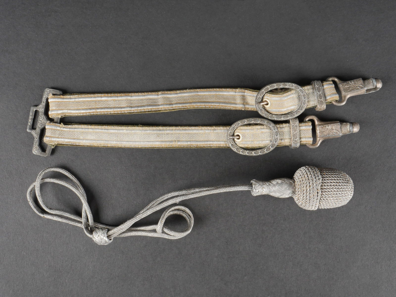 Accessoires de dague allemand. German dagger accessories: Accessoires de dague allemande. Comprend une dragonne complete en fil argente et une paire de belieres dites de luxe en velours vert avec galons argentes. Garnitures metalliques a decor de feuilles de
