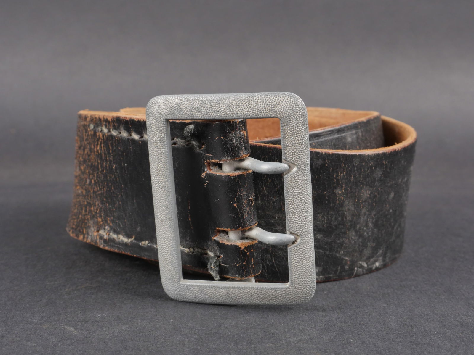 Ceinturon officier de la Heer. German officer belt.: Ceinturon de la Heer. Modele d’officier en cuir noir avec boucle grenelee argentee. Deux ardillons complets. Marquage du fabricant illisible. Presence de l’aigle Waa. Presente une usure et une pat