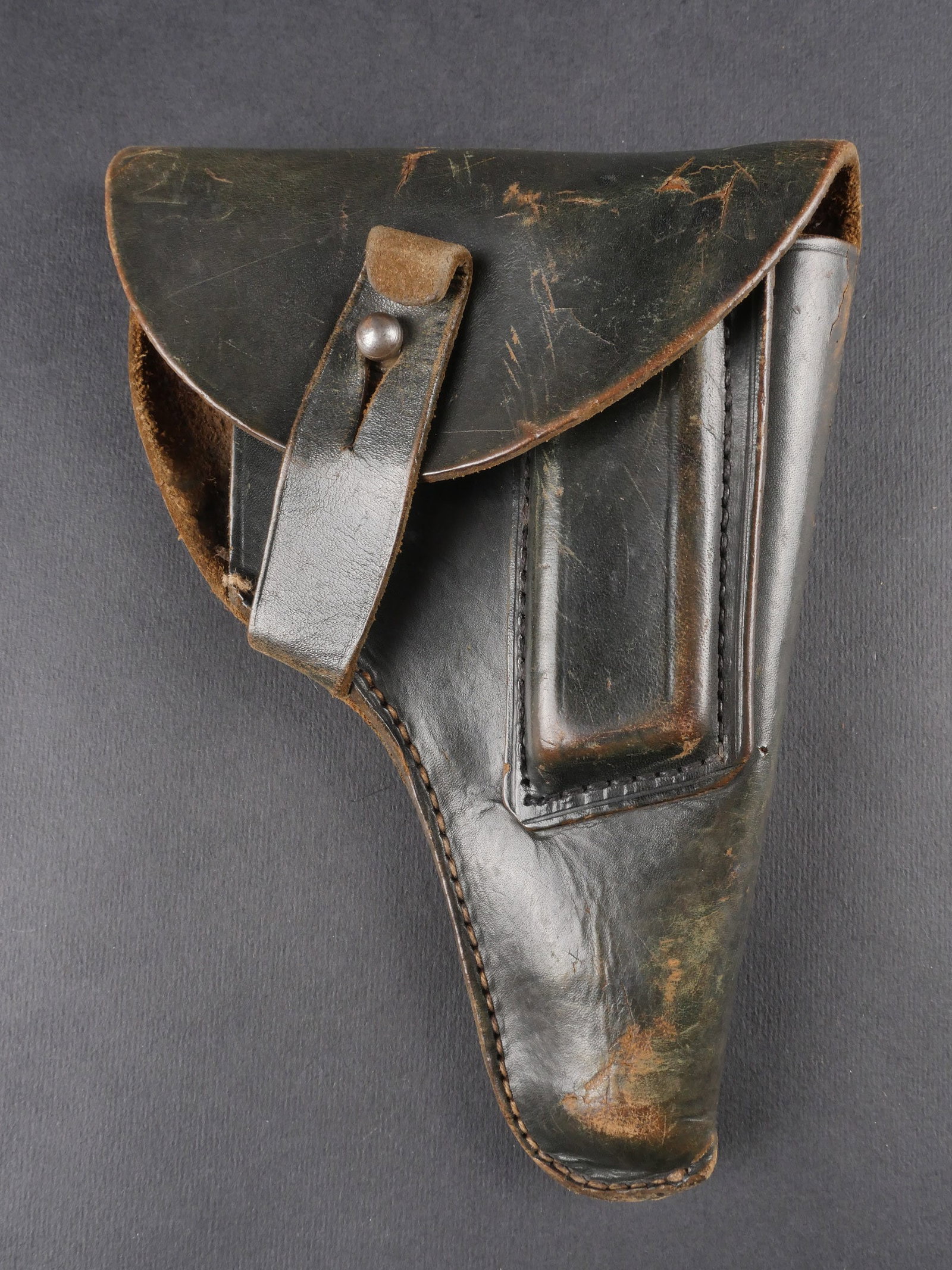 Holster de pistolet allemand. German pistol holster: Holster de pistolet allemand. En cuir noir lisse. Sangle de fermeture complete. Passant arriere maintenu par deux rivets. Traces de couture visibles au dos. Marquages S HN B. Usure moderee et patine n