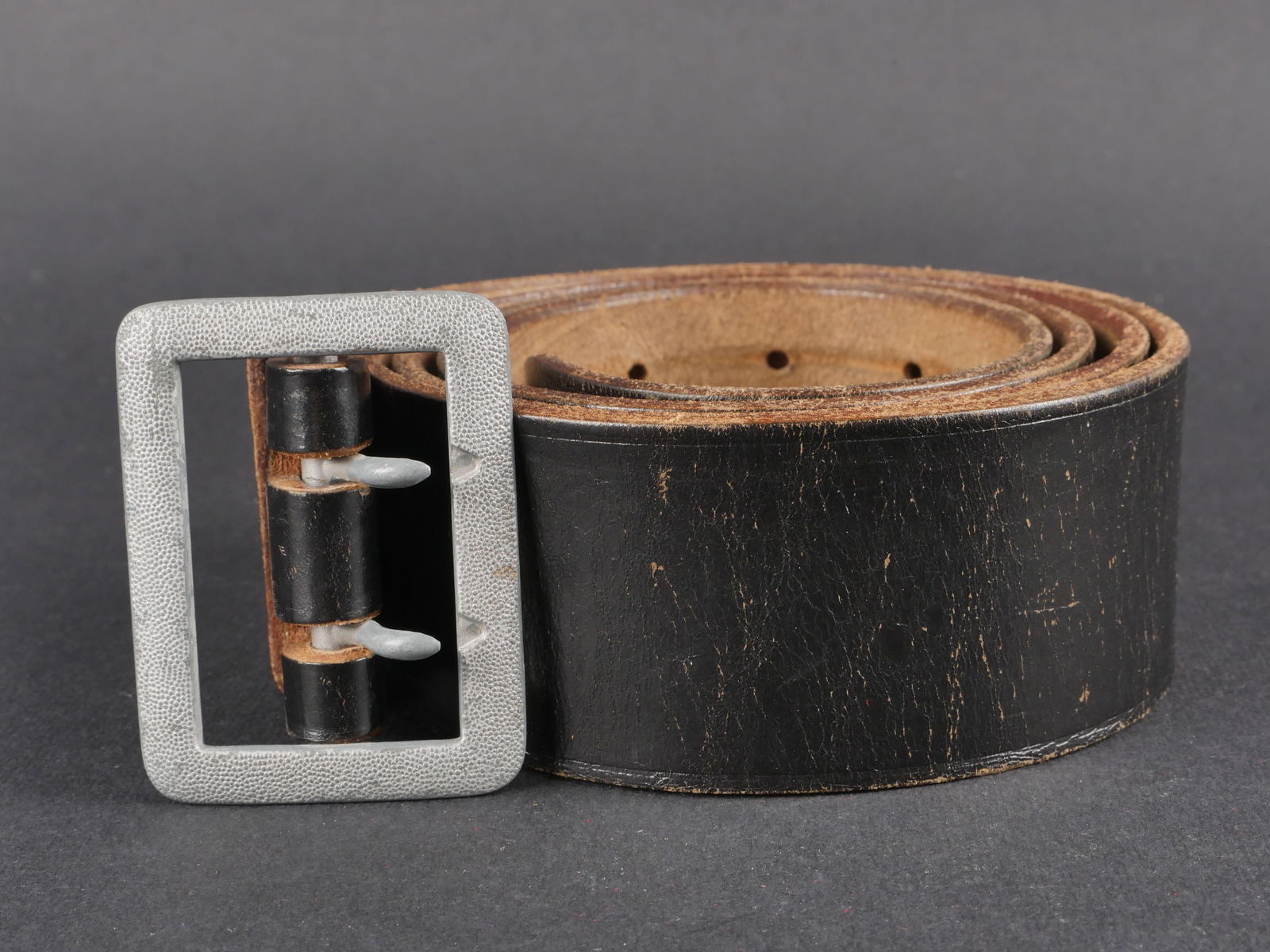 Ceinturon officier Heer. Heer officer belt.: Ceinturon d’officier de la Heer en cuir noir avec passant present. Boucle a deux ardillons en metal grenele. Taille 125. Marquage regimentaire Reg Col Goring. Presente une certaine usure et patine.