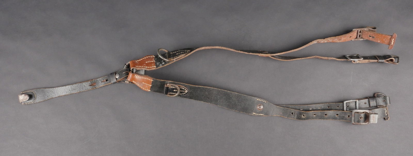 Brelage lourd. German Y Strap.: Brelage lourd en cuir bicolore noir et marron. Crochets en metal avec reste de peinture a 40 %. Marquages RBNR 0/0489/0002. Usure et patine d’usage. Etat II+. Heavy Y-strap in black and brown leathe