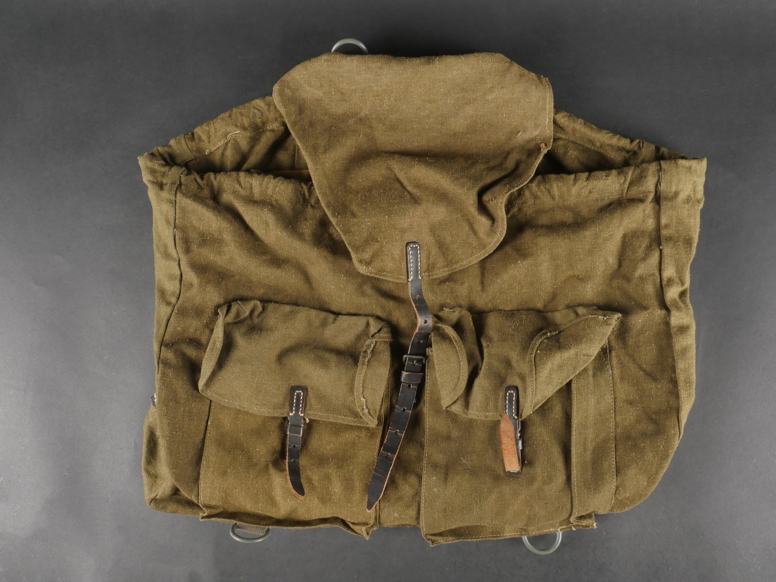 Sac a dos allemand. German backpack: Sac a dos allemand en toile feldgrau epaisse et cuir noir. Le cordon de serrage est present. Deux anneaux sur support en toile gris bleute. Marquages illisibles. a noter une legere usure et patine de 