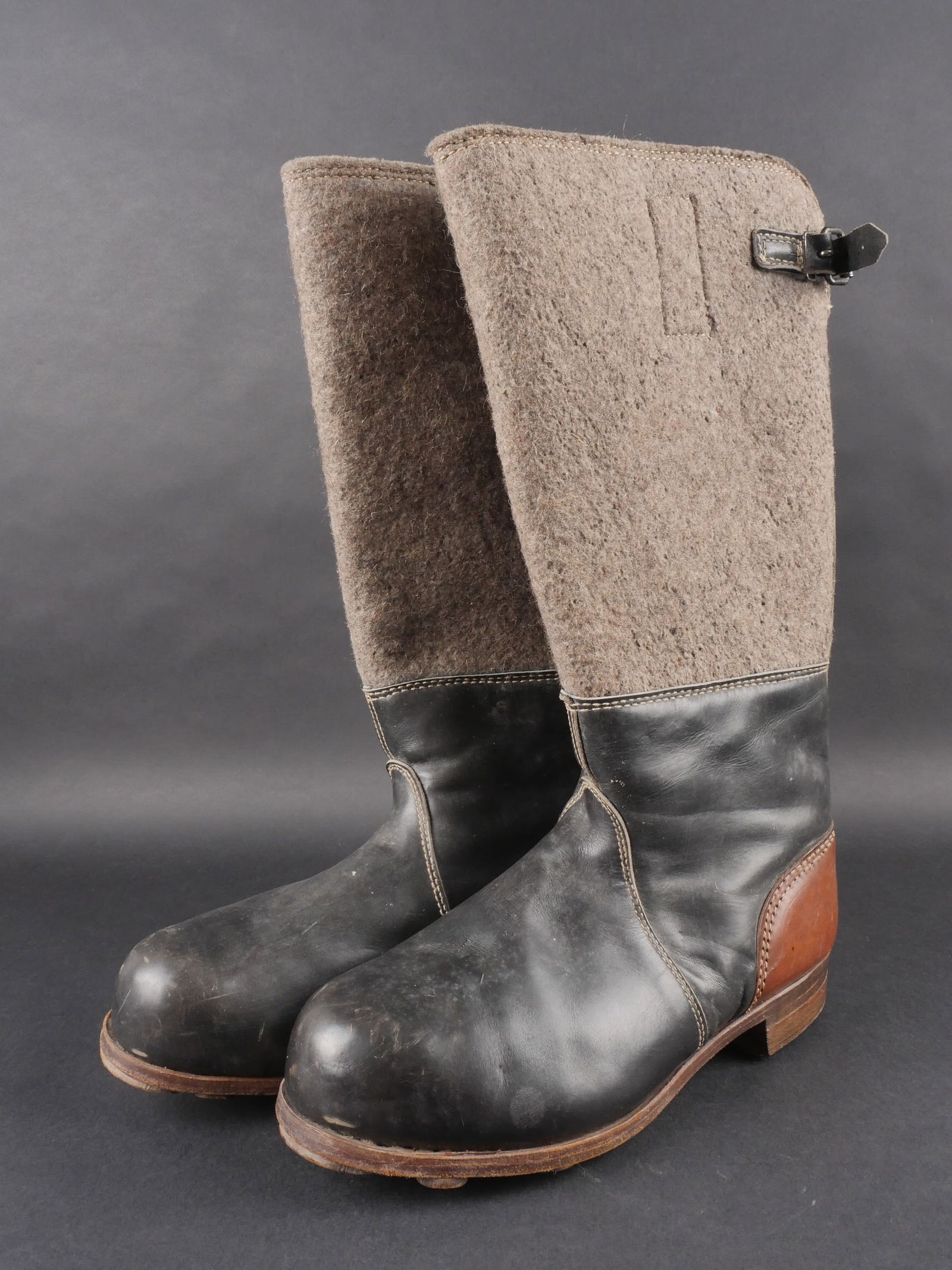 Bottes en feutre allemande. German felt boots: Bottes hivernales en feutre avec tiges hautes en epais feutre gris. Cuir bicolore noir et marron souple et en tres bon etat. Pattes de fermeture completes. Semelles en cuir avec renforts de tampons en