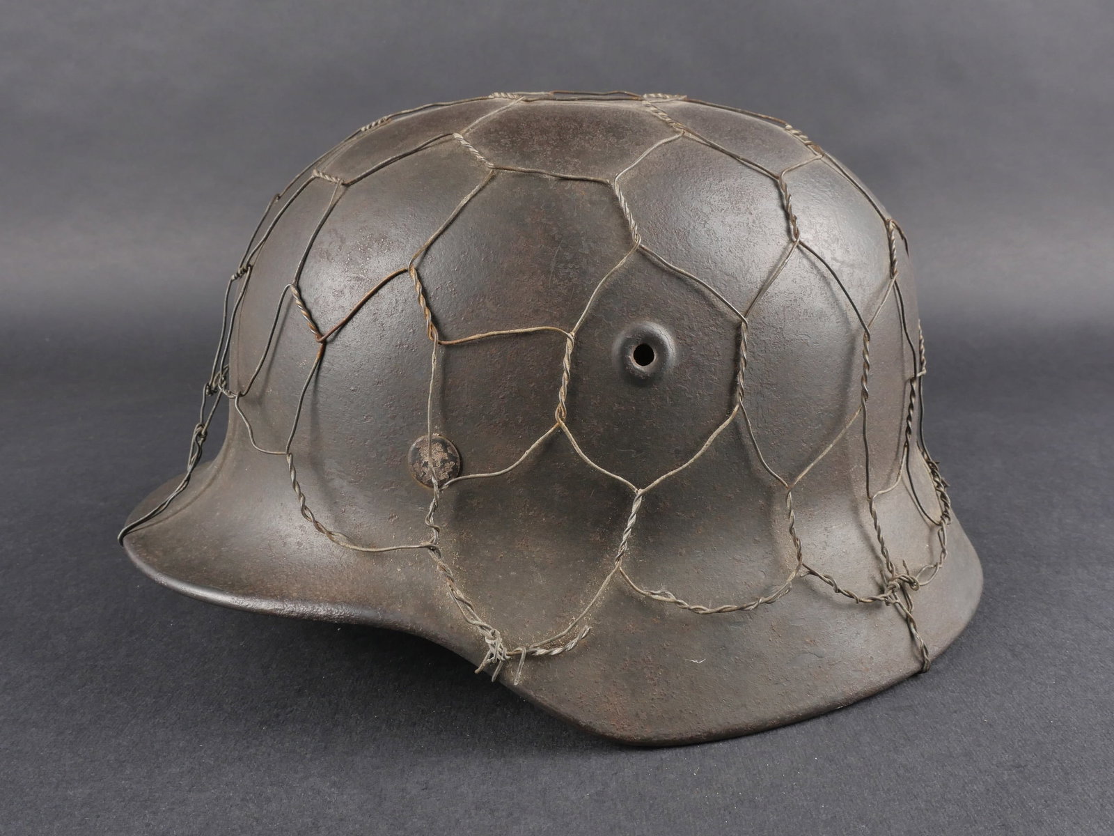 Casque grillage allemand. German helmet with wire camouflage: Casque allemand grillage, modele M-40, fabrication Q66, numero de lot DN596. Coiffe en cuir complete, taille estimee a 58 ou 59. Jugulaire en cuir complete avec marquages illisibles. Cordon de serrage