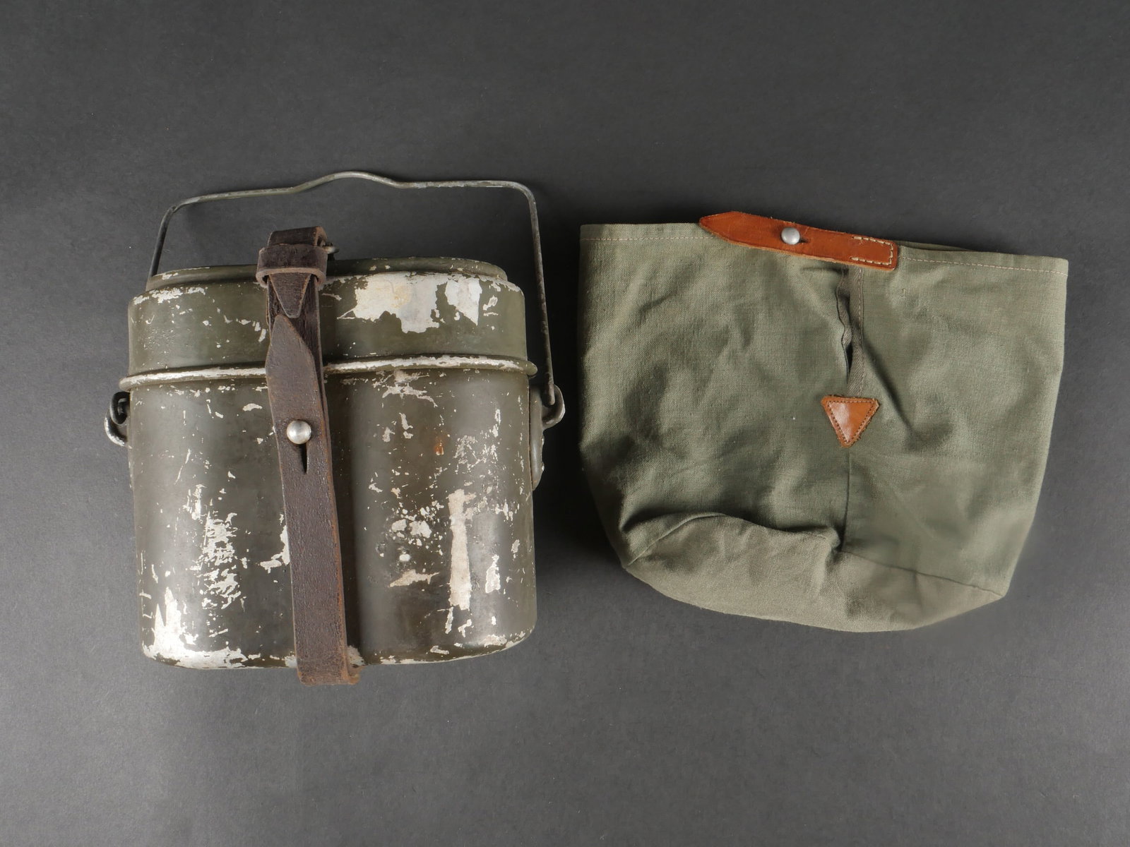 Gamelle allemande. German mess tin: Gamelle allemande. En aluminium, peinture Feldgrau a 70 %. Poignee de transport complete. Fabrication FWBN 39 (couvercle) et HRE 39 (corps). Sangle en cuir brun, complete mais non marquee. Accompagnee