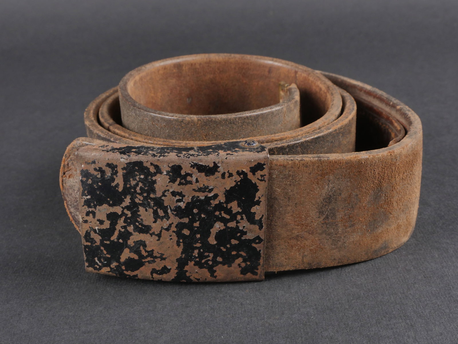 Ceinturon des troupes disciplinaire. Belt from disciplinary troops: Ceinturon des troupes disciplinaires en cuir noir, equipe d’une bouclerie en metal recouverte a 70 % de peinture Feldgrau. Patte de reglage complete. Taille 120. Aucun marquage apparent. Boucle de c
