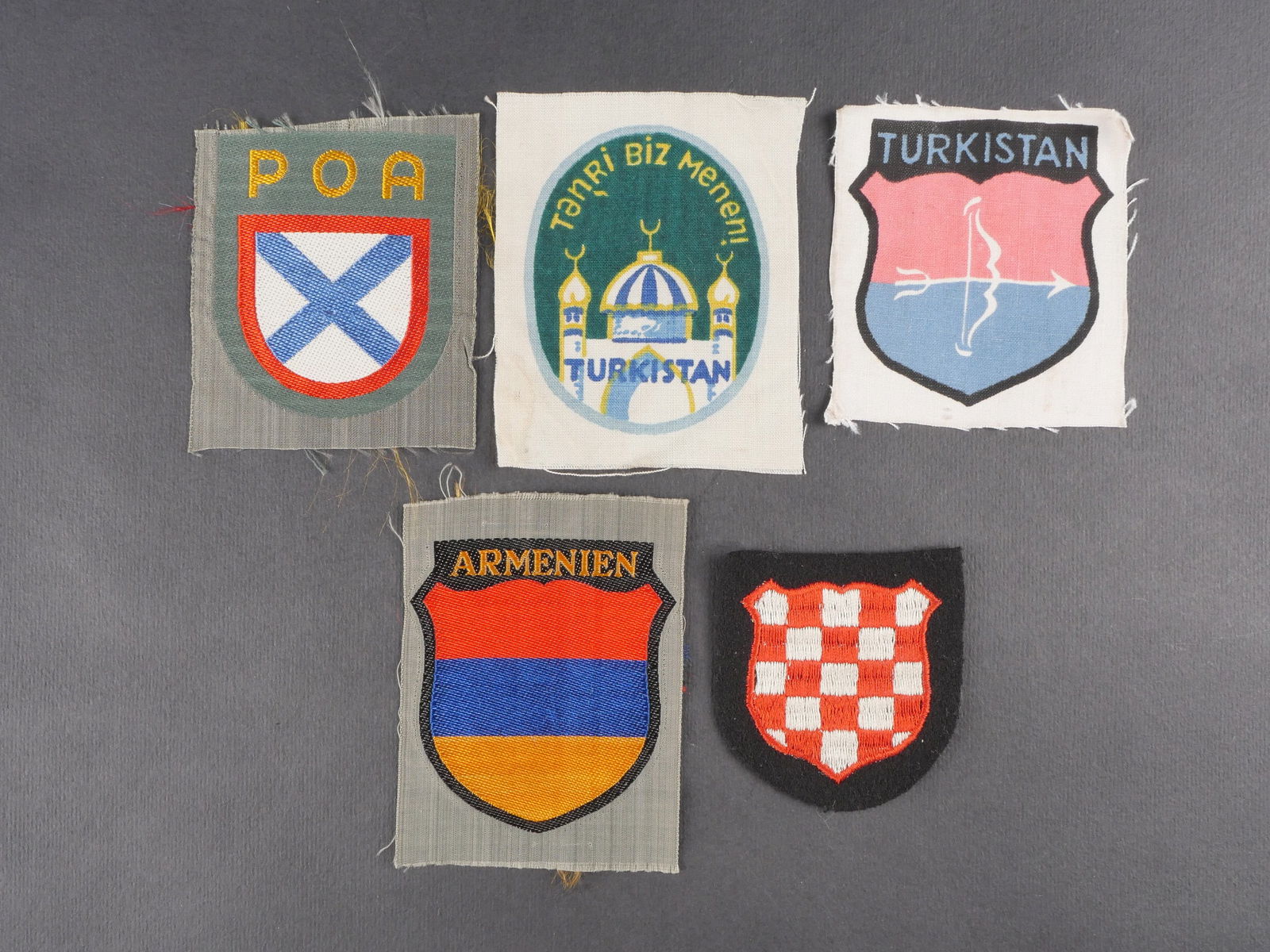 Insignes de volontaires etrangers. Foreign volunteer insignia: Ensemble d’insignes de volontaires etrangers comprenant un insigne Bevo POA jamais monte, un insigne Bevo Armenien jamais monte, deux insignes imprimes Turkistan jamais montes, ainsi qu’un insigne