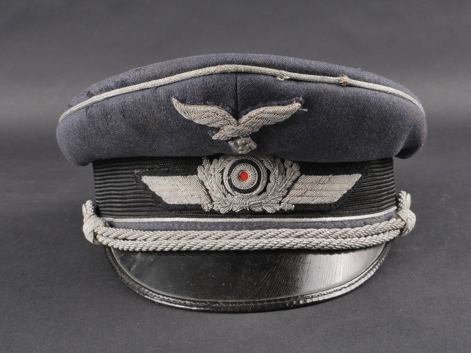 Casquette d officier LW. Luftwaffe visor cap.: Casquette d’officier de la Luftwaffe en drap gris-bleu. Aigle et cocarde en cannetille argent cousus main. Bandeau en mohair avec triple lisere argent. Fausse jugulaire allemande. Visiere en bon eta