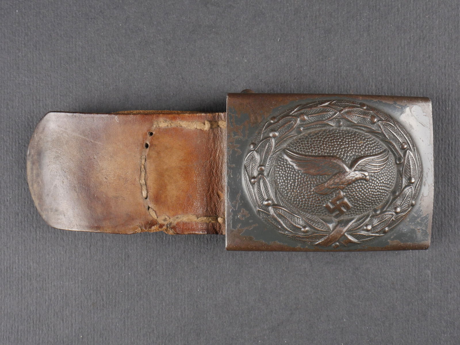 Boucle de ceinturon LW. Luftwaffe Belt buckle.: Boucle de ceinturon de la Luftwaffe. En metal, peinture gris-bleu a 50 %, aigle du second type. Sans marquages visibles. Boucle a deux ardillons complete. Patte en cuir presente, couture defaite. Fabr