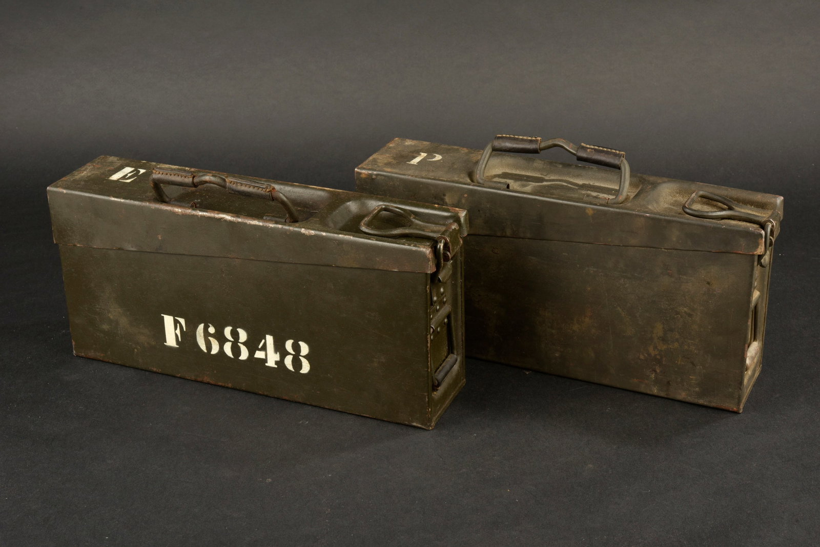 Caisses MG allemande. German MG ammunition boxes: Caisses MG allemandes comprenant une caisse en metal avec une peinture conservee a 90 %. Les renforts en cuir aux poignees sont presents. Un marquage lateral a la peinture blanche est visible, avec l�