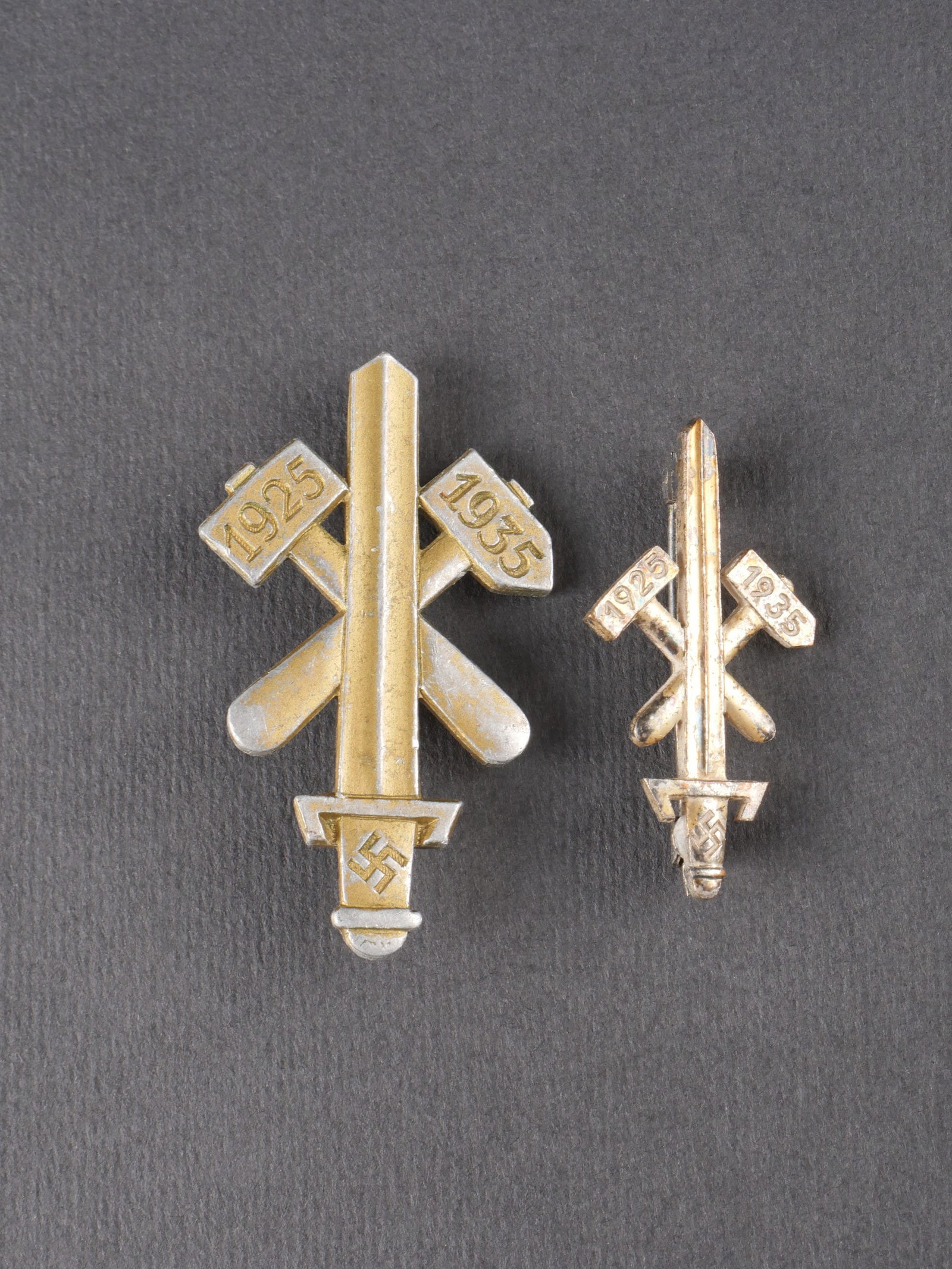 Insignes 1925-1935. 1925-1935 insignia.: Deux insignes dates de 1925 a 1935, de modeles distincts. Les dorures sont partiellement conservees a hauteur de 50 % et 60 %. Les attaches sont presentes, mais les marquages demeurent illisibles. Usu