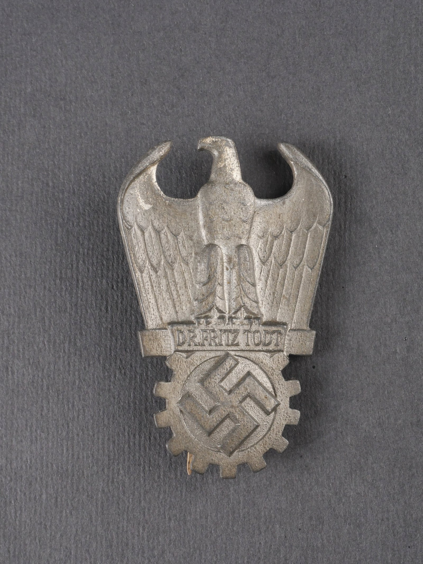Insigne Fritz Todt. Fritz Todt badge.: Insigne Fritz Todt en metal, de fabrication lourde, de couleur argent, avec attache complete. Fabrication numero 20. Presente une usure et une patine caracteristiques. etat II+. Fritz Todt badge in he