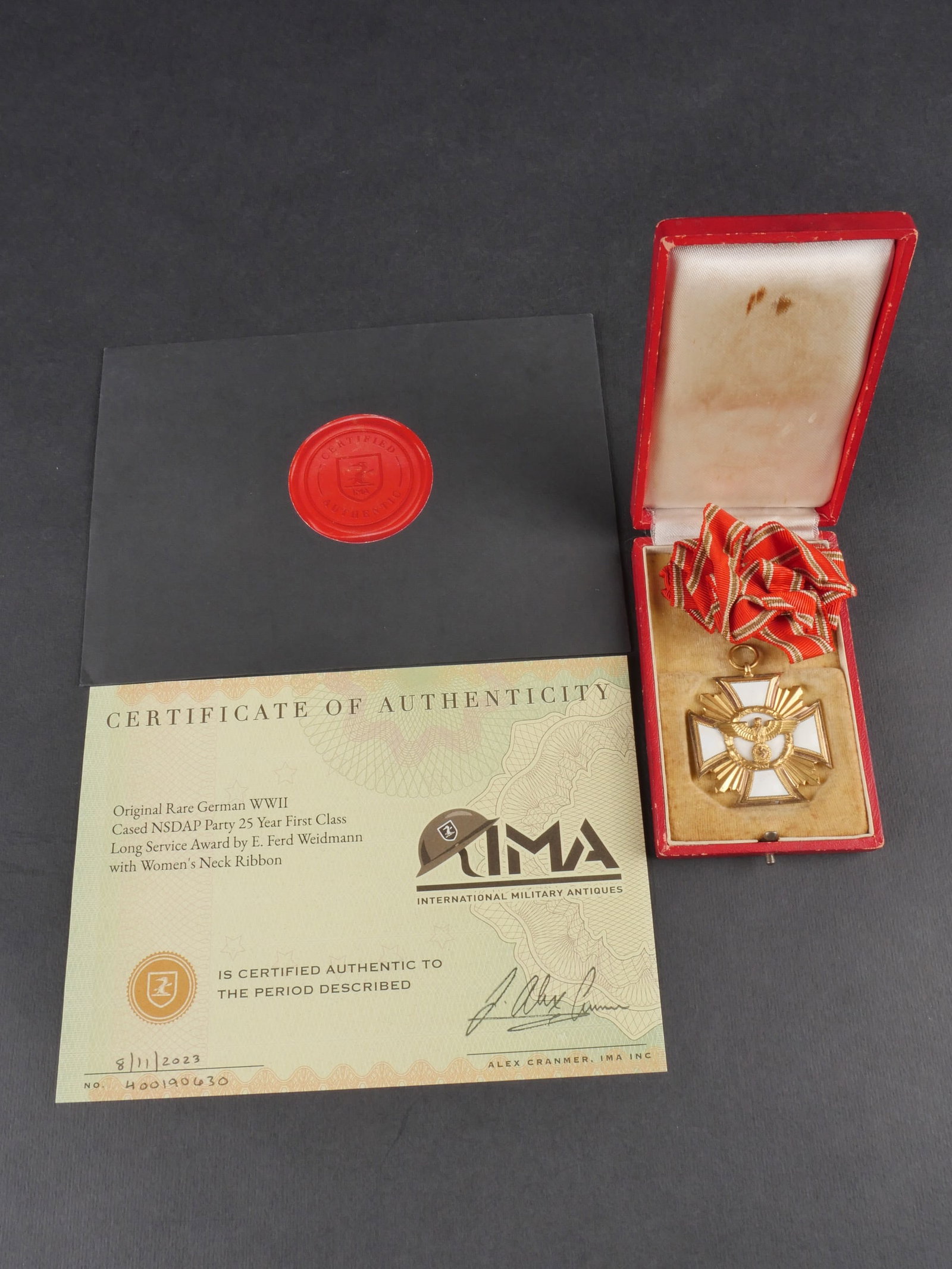 Medaille de 25 ans de service pour femme NSDAP. 25-Year NSDAP Women s Service Medal: Medaille pour 25 ans de service des femmes du NSDAP, decoration tres rare. Presentee dans un coffret rouge avec fermoir complet et bel aigle dore sur le couvercle. Quelques taches visibles sur la boit