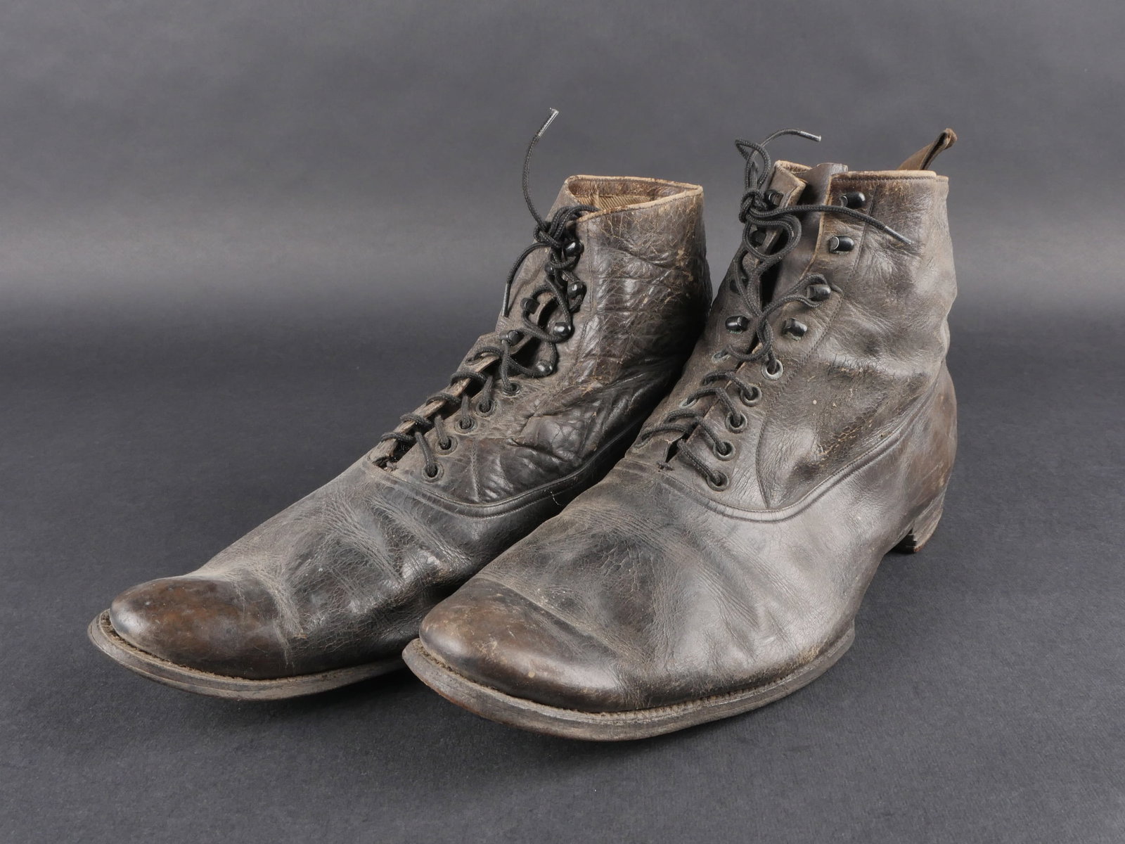 Brodequin dofficier japonais. Japanese officer’s ankle boot: Brodequins d’officier japonais, en cuir noir homogene. Dotes de cinq œillets et quatre crochets de lacage. Lacets posterieurs. Semelles et talons fortement uses. Reste de marquages illisibles. Une 