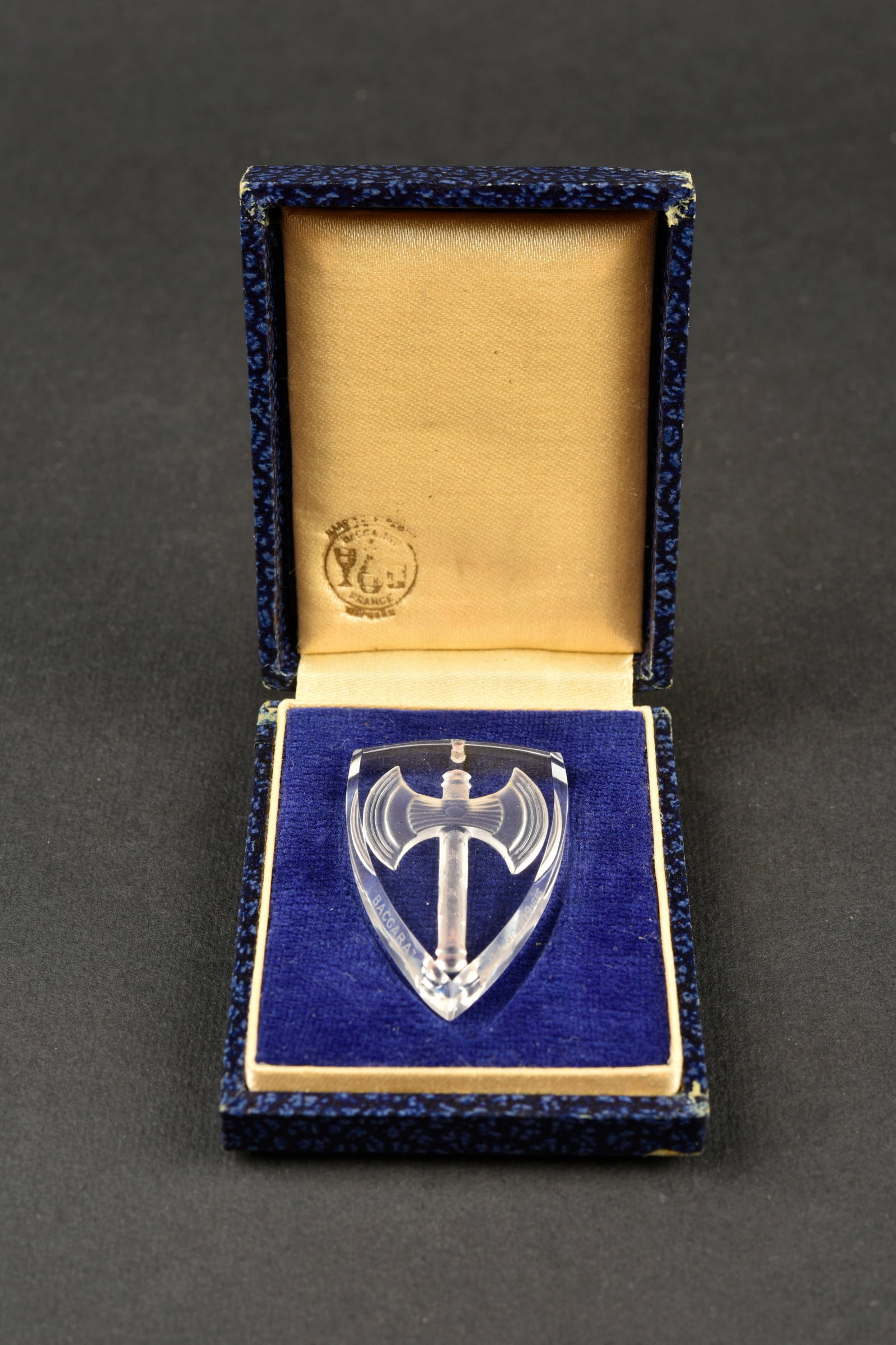 Ecusson a la Francisque en Cristal de Baccarat. Francisque Emblem in Baccarat Crystal: Ecusson a la Francisque en Cristal de Baccarat En forme d’ecu francais (4,7 cm), signe Baccarat et numerote OA90009 BIS. Boite bleue soyeuse avec logo Baccarat France. Francisque badge in Baccarat c