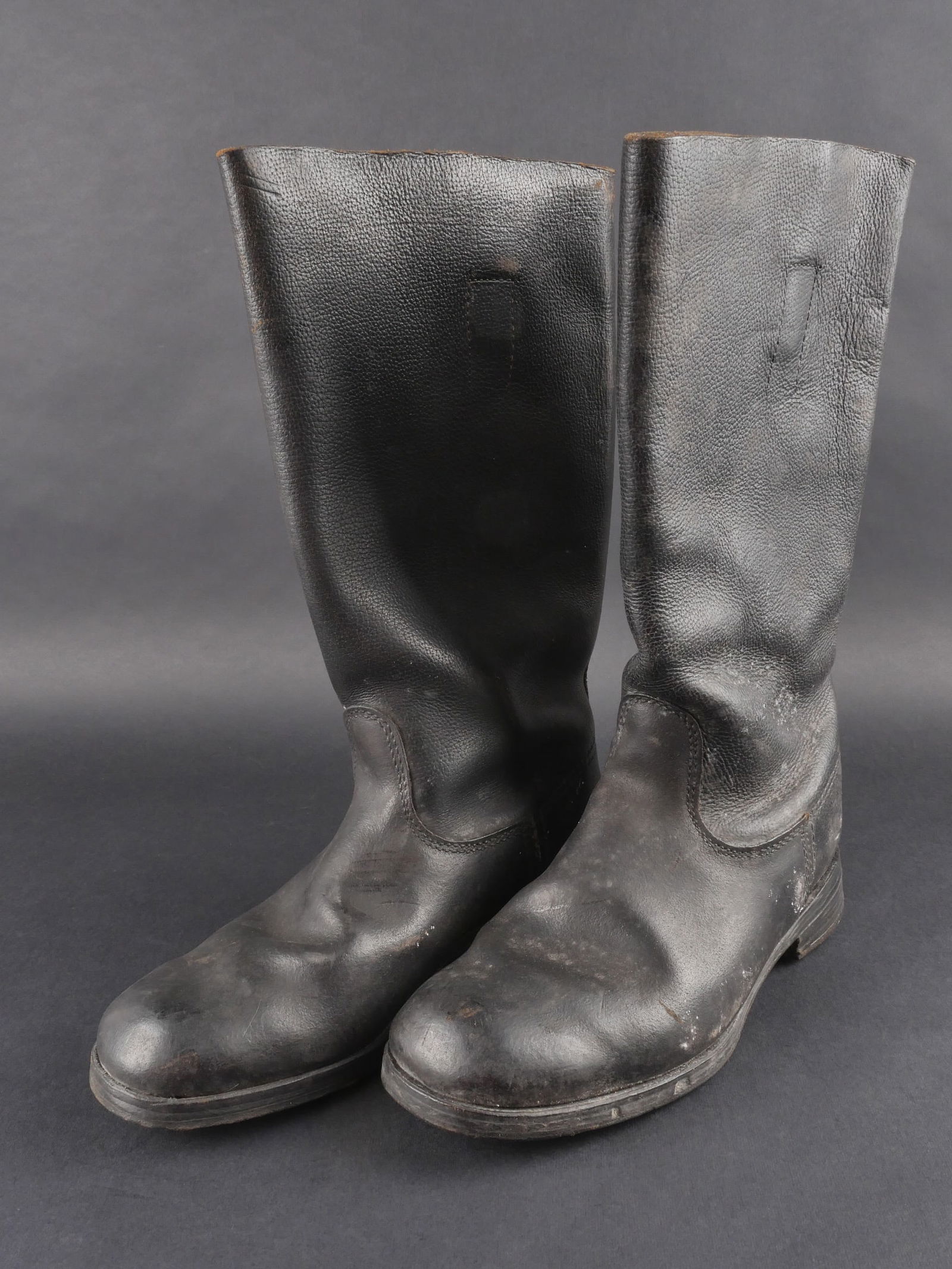 Bottes type allemande. German style boots.: Bottes de type allemand, paire homogene en epais cuir grenele. Marquages internes illisibles. Semelles en cuir lisse, talons partiellement ferres et renforts en caoutchouc. Pointure estimee a 43 ou 44
