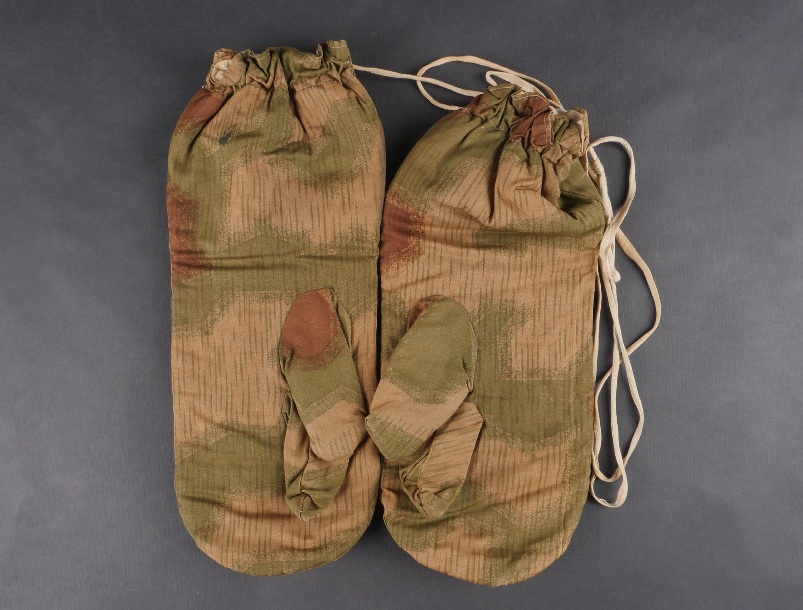 Gants camoufle Heer. Heer camouflage gloves: Gants camoufles Heer, paire de moufles homogene en tissu camoufle flou reversible blanc. Les cordons sont presents. Marquage au tampon Reichs-Betriebs-Nr 0/0250/0884. a noter une legere usure et patin