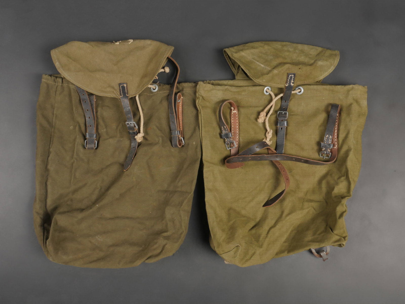 Sacs a dos allemand. German backpacks: Sacs a dos allemands. Deux sacs d allegement en forte toile Feldgrau et cuir noir. Toutes les sangles et cordons de serrage sont presents. Les bretelles sont manquantes. Marquages illisibles. L un des