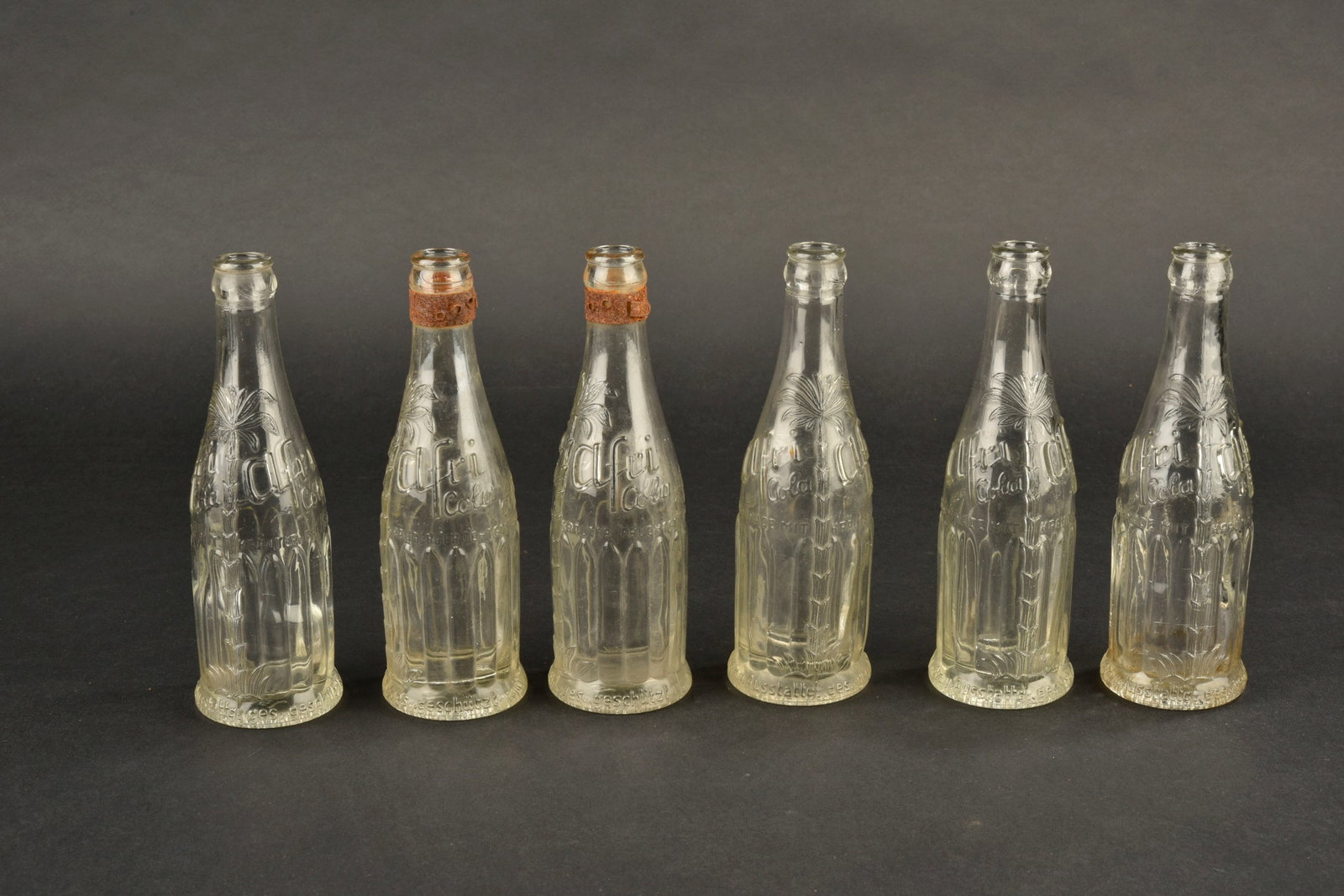 Bouteilles Afrikola. Afrikola bottles.: Bouteilles Afrikola en verre blanc, lot de six. Les bouchons sont manquants. Marquages Afrikola visibles. Mention du fabricant Afri Urprodukte Bluna Koln 18. L ensemble presente une certaine usure et 