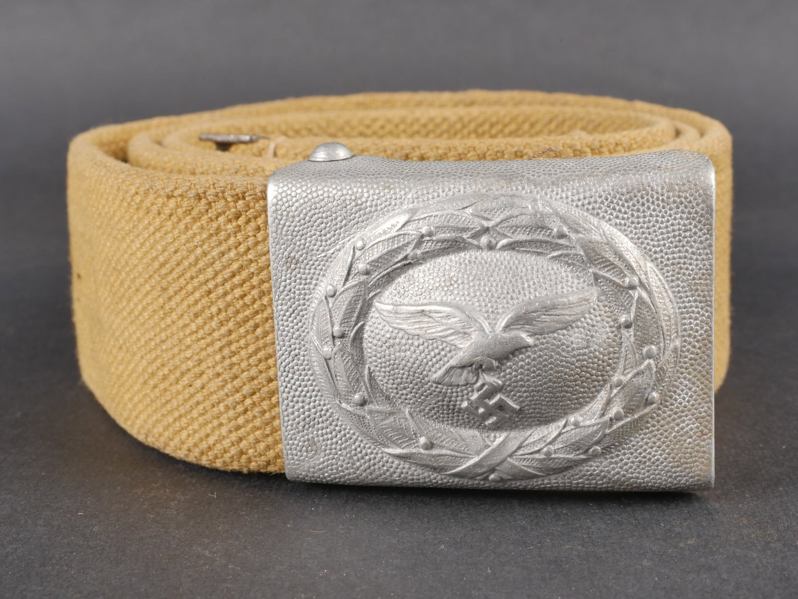 Ceinturon tropical LW. Luftwaffe tropical belt.: Ceinturon tropical de la Luftwaffe en forte toile de couleur jaune sable. Bouclerie en metal avec peinture feldgrau conservee a 80 %. Patte de reglage en cuir complete. Lettre M realisee au pochoir. T