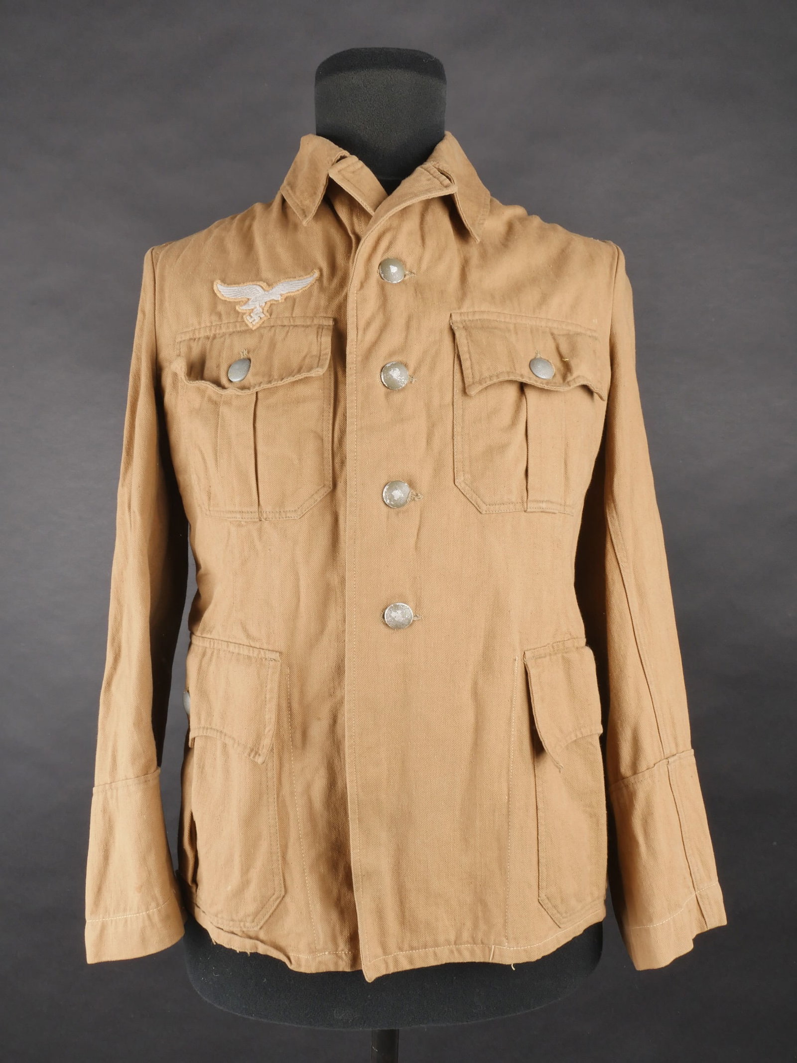 Vareuse tropicale LW. Luftwaffe tropical jacket.: Vareuse tropicale de la Luftwaffe en forte toile de coton beige. Tous les boutons sont presents et majoritairement en couleur feldgrau d’origine. Reproduction d’aigle de poitrine. Nombreuses repar