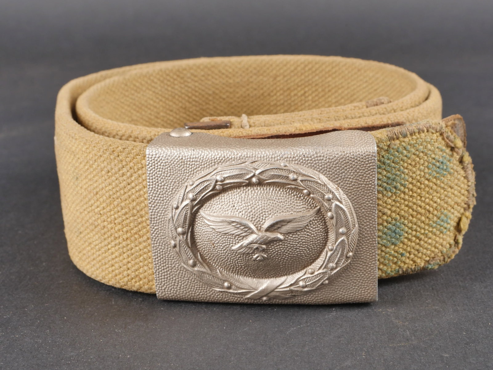 Ceinturon tropical LW. Luftwaffe tropical belt.: Ceinturon tropical de la Luftwaffe en forte toile de couleur jaune sable. Bouclerie en metal avec peinture feldgrau conservee a 50 %. Patte de reglage en cuir complete. Taille 90. Aucun marquage visib