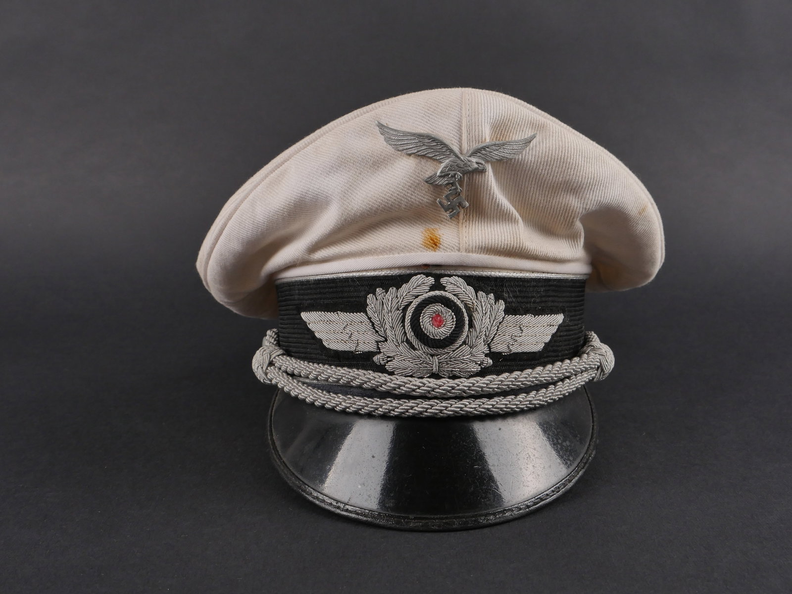 Casquette d officier de la LW. Luftwaffe visor cap.: Casquette d’officier de la Luftwaffe en coton blanc. Aigle metallique non demonte. Cocarde et feuilles de chene en cannetille argentee. Fausse jugulaire argentee. Double lisere argent. Coiffe amovib