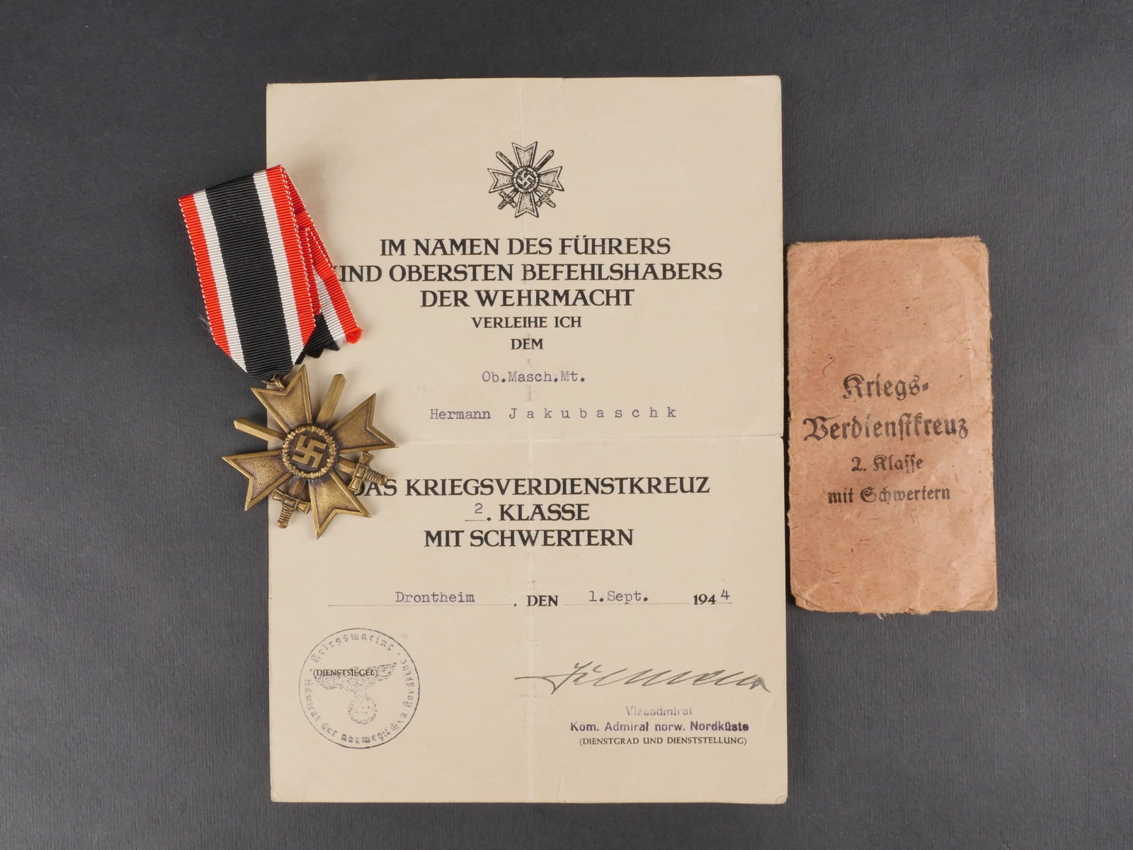 Diplome de la KVK. KVK diploma: Diplome de la Kriegsverdienstkreuz comprenant un document en papier pour une KVK de seconde classe avec epees, au nom de l’OB Masch MT Hermann Jakubaschk. Attribue a Drontheim le 1er septembre 1944 