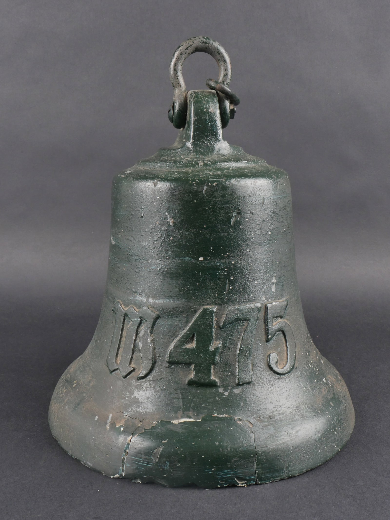 Cloche Kriegsmarine. Kriegsmarine bell.: Cloche de la Kriegsmarine en metal, reparation maladroite a la resine sur la bordure. Attache mobile complete, marteau present. Aigle allemand en relief, marquage « M475 ». Peinture verte type jardi