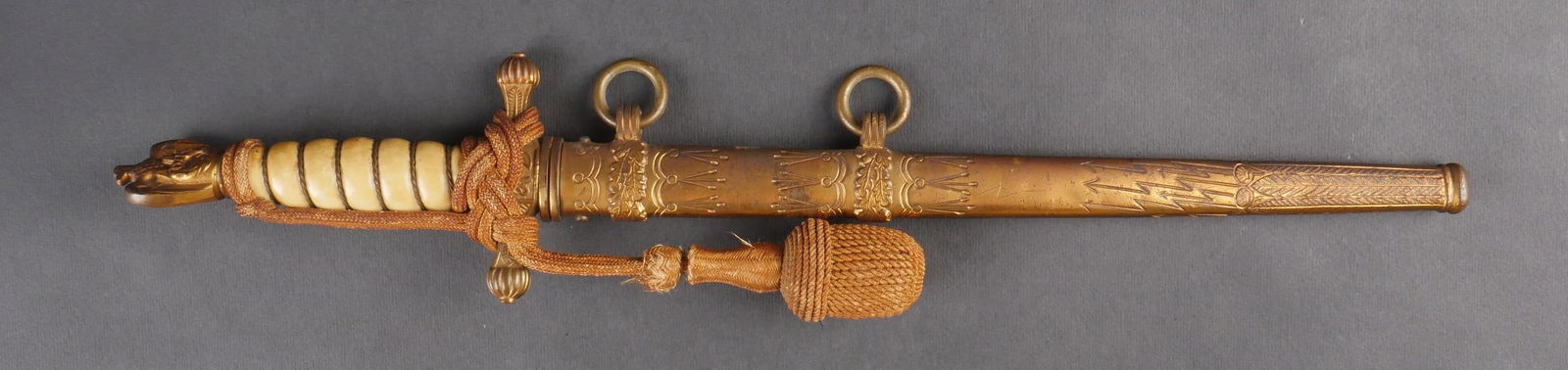 Dague Kriegsmarine. Kriegsmarine dagger.: Dague d’officier de la Kriegsmarine. Garnitures dorees. Poignee en celluloid blanc avec filigrane complet. Dragonne en fil dore fixee selon les normes reglementaires. Bouton poussoir fonctionnel. Fo