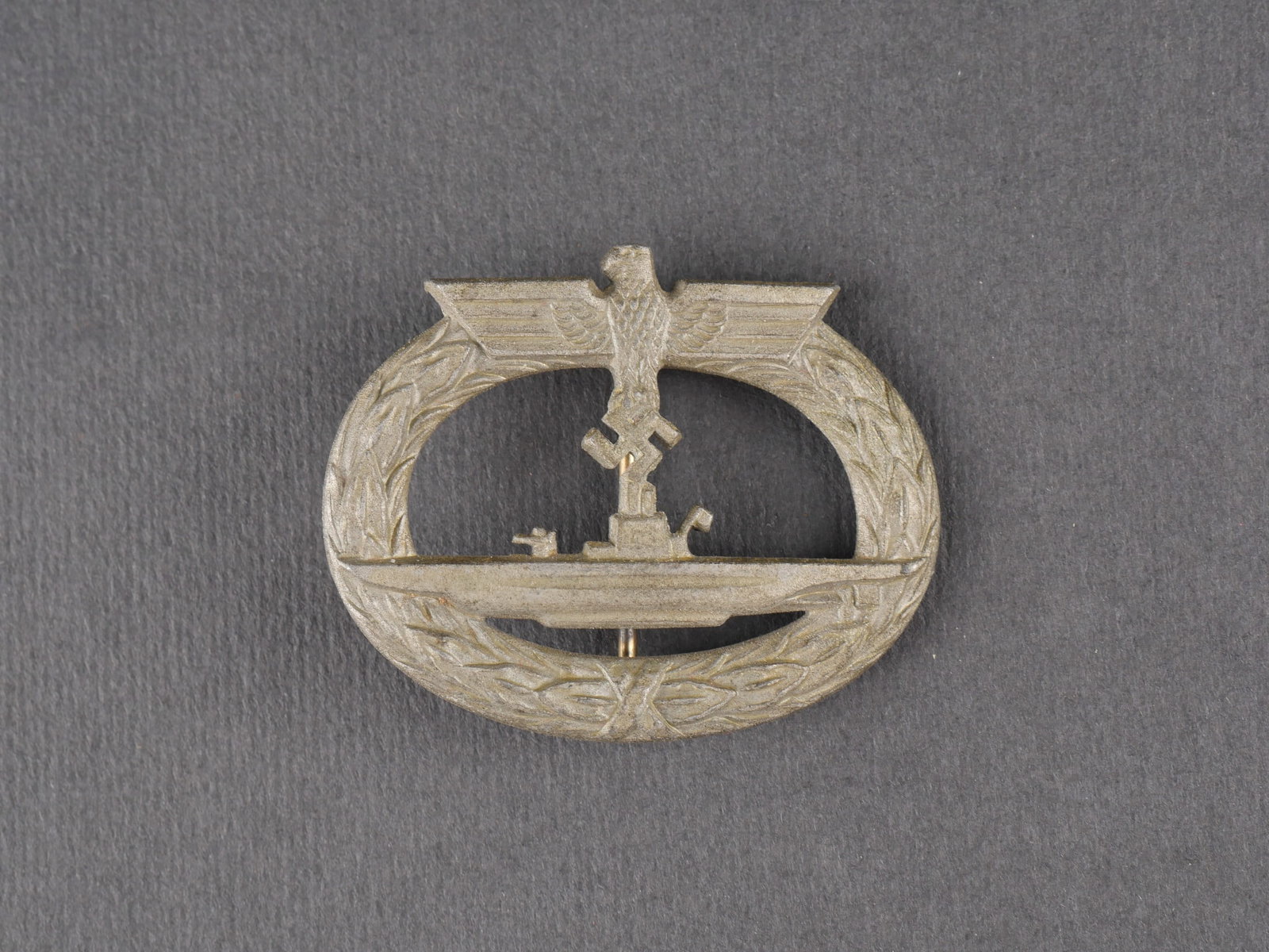 Insigne UBOOT. German UBOOT insignia.: Insigne de sous-marin (U-Boot) en metal, dorure quasiment absente. Attache complete. Fabrication GWL. Presente une certaine usure et patine. etat II. U-Boat badge in metal with almost no remaining gil
