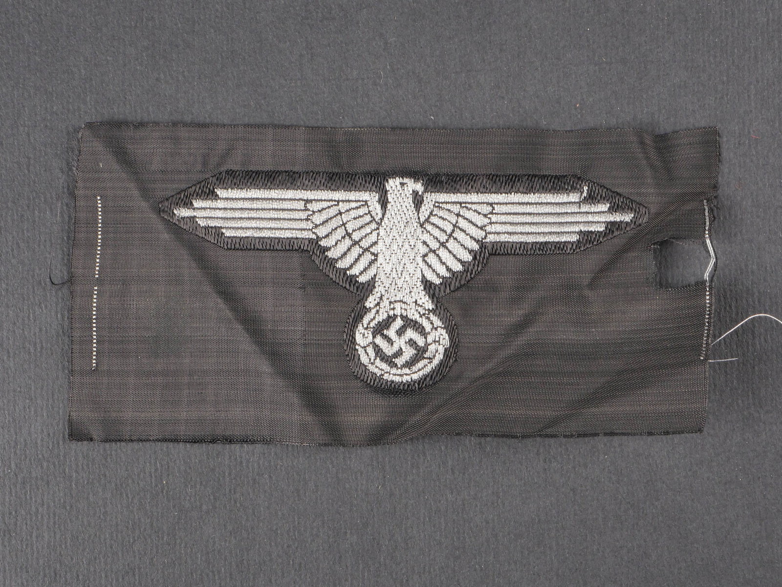 Aigle de manche SS. SS sleeve eagle.: Aigle de manche SS, modele Bevo jamais monte, manque de tissu lateral. Traces de scotch. Usure et patine visibles. etat II+. SS sleeve eagle, Bevo-woven model, never mounted, missing side fabric. Tape