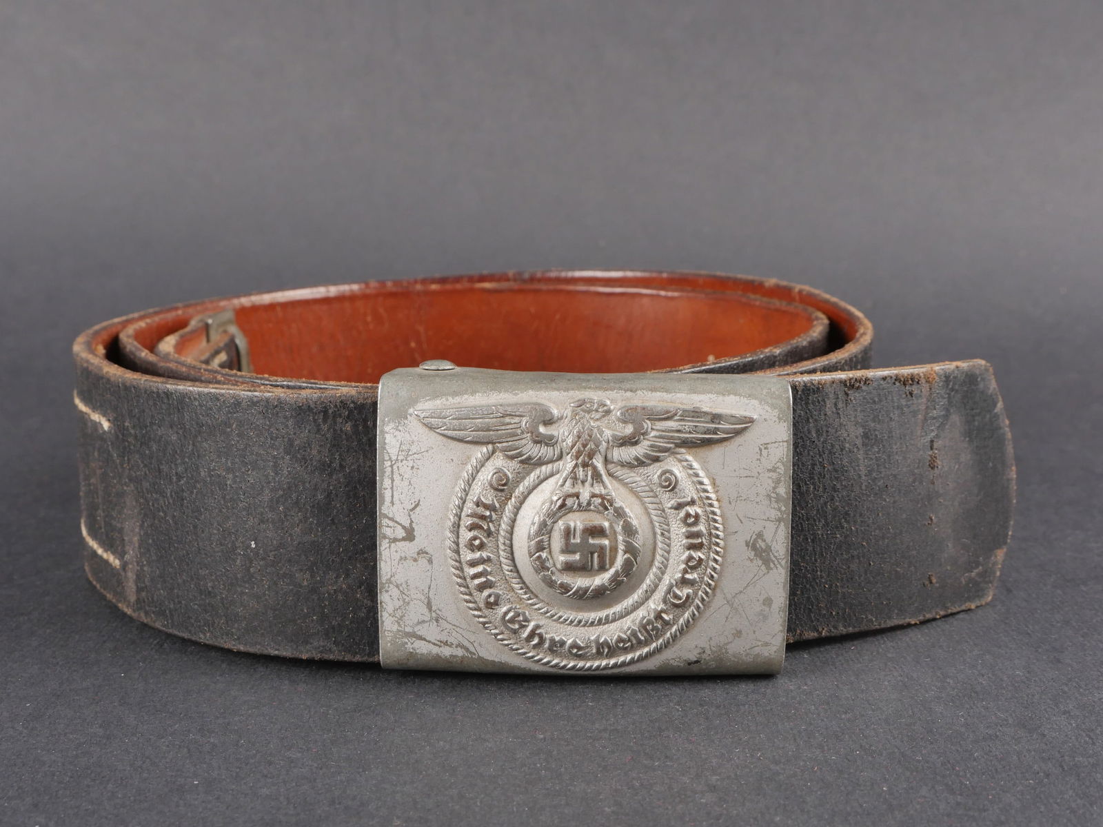 Ceinturon SS. German SS Belt.: Ceinturon de troupe de la Waffen-SS en cuir noir complet, avec bouclerie en metal conservee a 80 % dans sa couleur d’origine. Patte de reglage complete. Taille 120. Marquages illisibles. Boucle en m