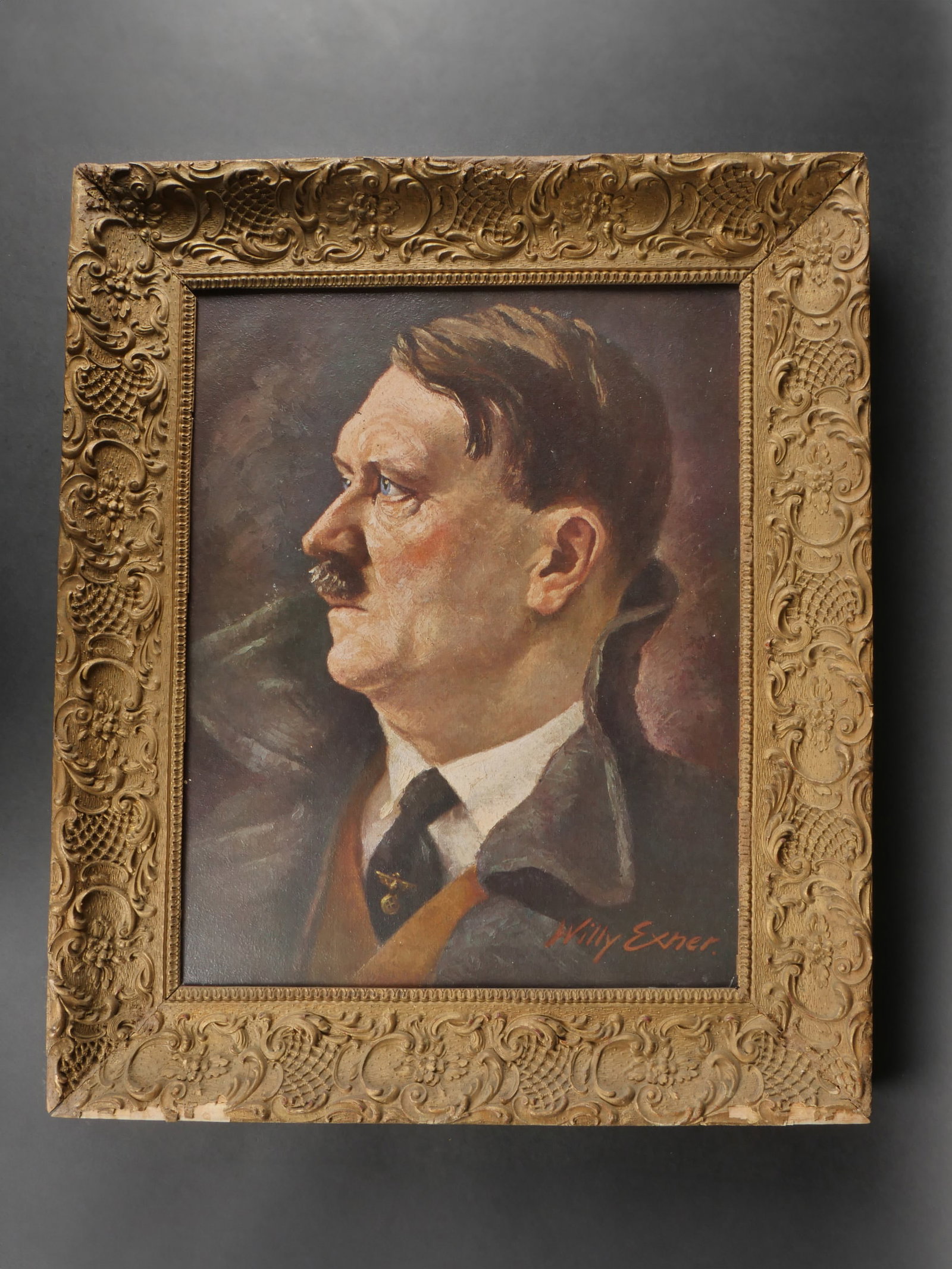 Portrait du Chancelier allemand. Portrait of the German Chancellor.: Portrait du Chancelier allemand, presente dans un cadre ancien orne de decors floraux en relief. Toile peinte figurant le Chancelier allemand, signee par l’artiste Willy Exner. Le dos comporte une e